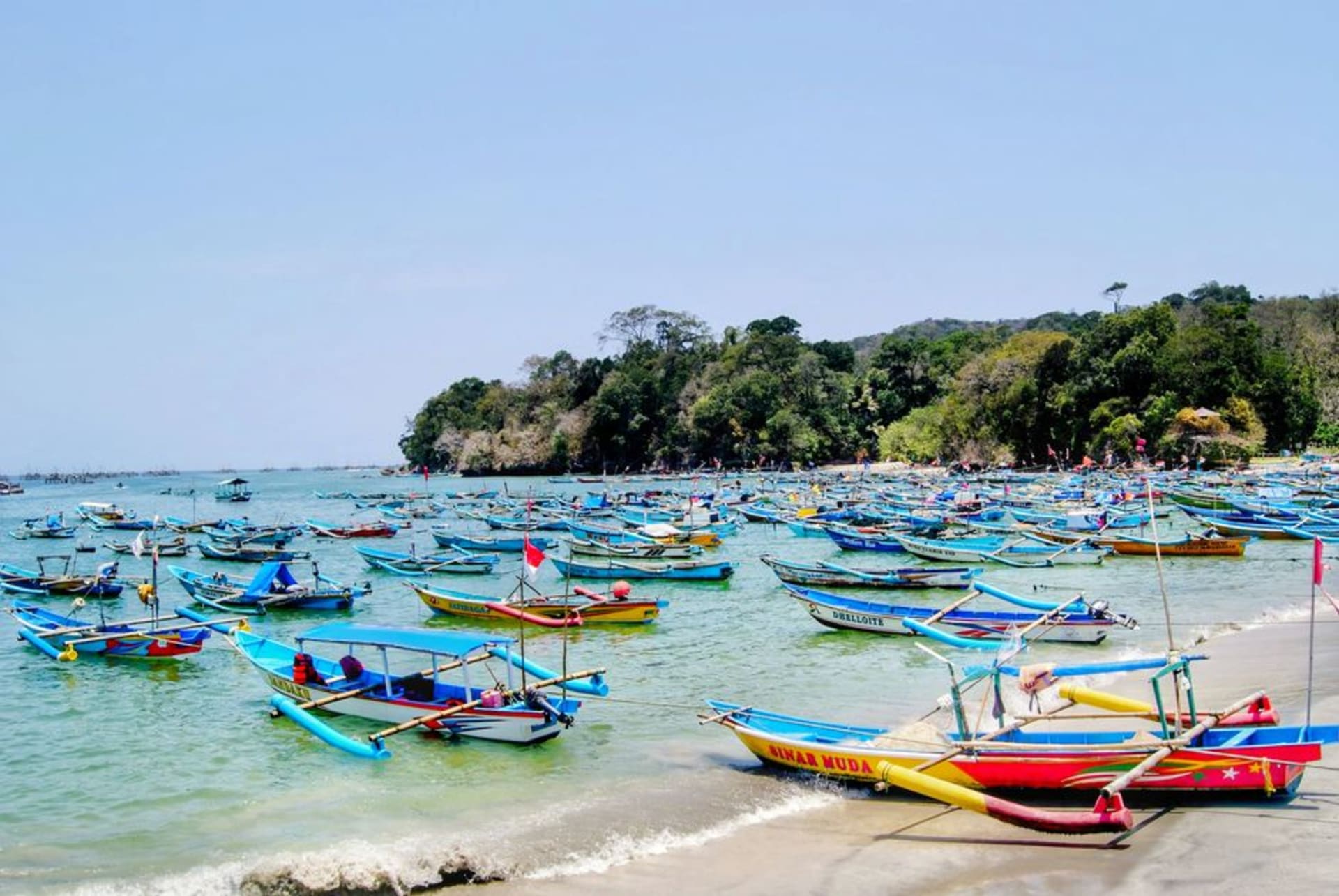 Wide sandy beach at Pangandaran with fishing boats and the peninsula headland in the distance
