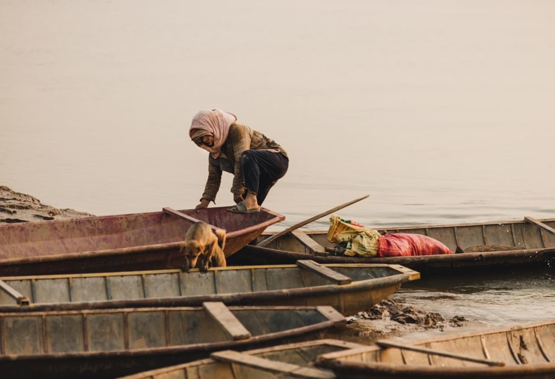 The wide Mahakam River at sunset lined with the city of Samarinda and traditional river boats