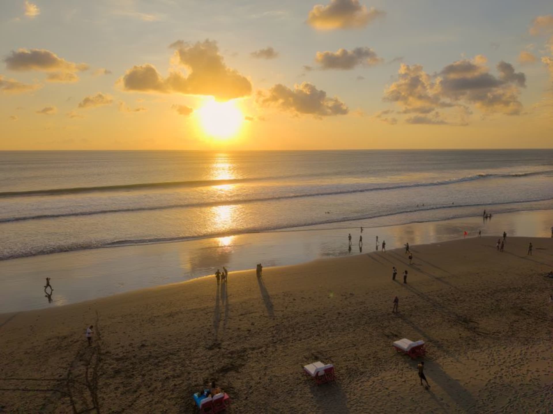 Sunset over the sand at Seminyak beach with silhouetted beach umbrellas