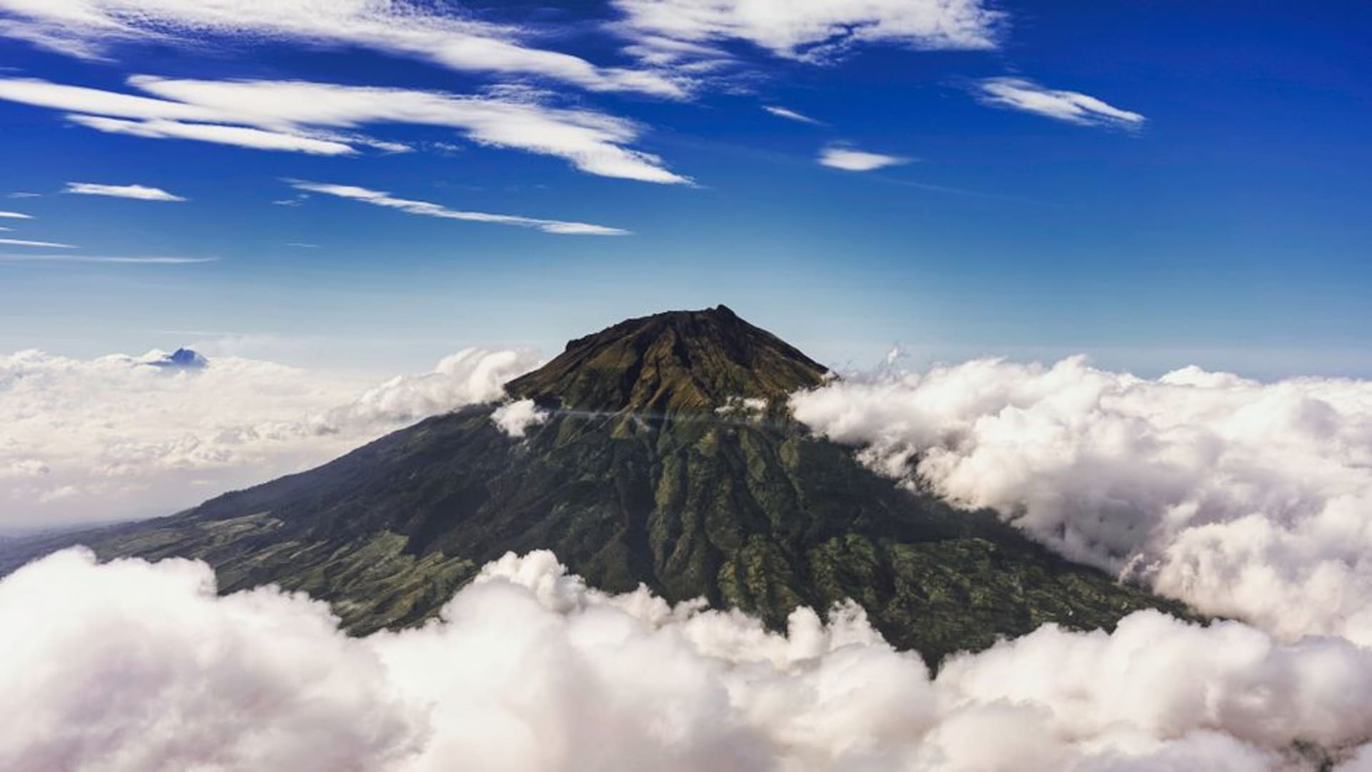 Symmetrical cone of Gunung Gamalama volcano rising above the coastal town of Ternate