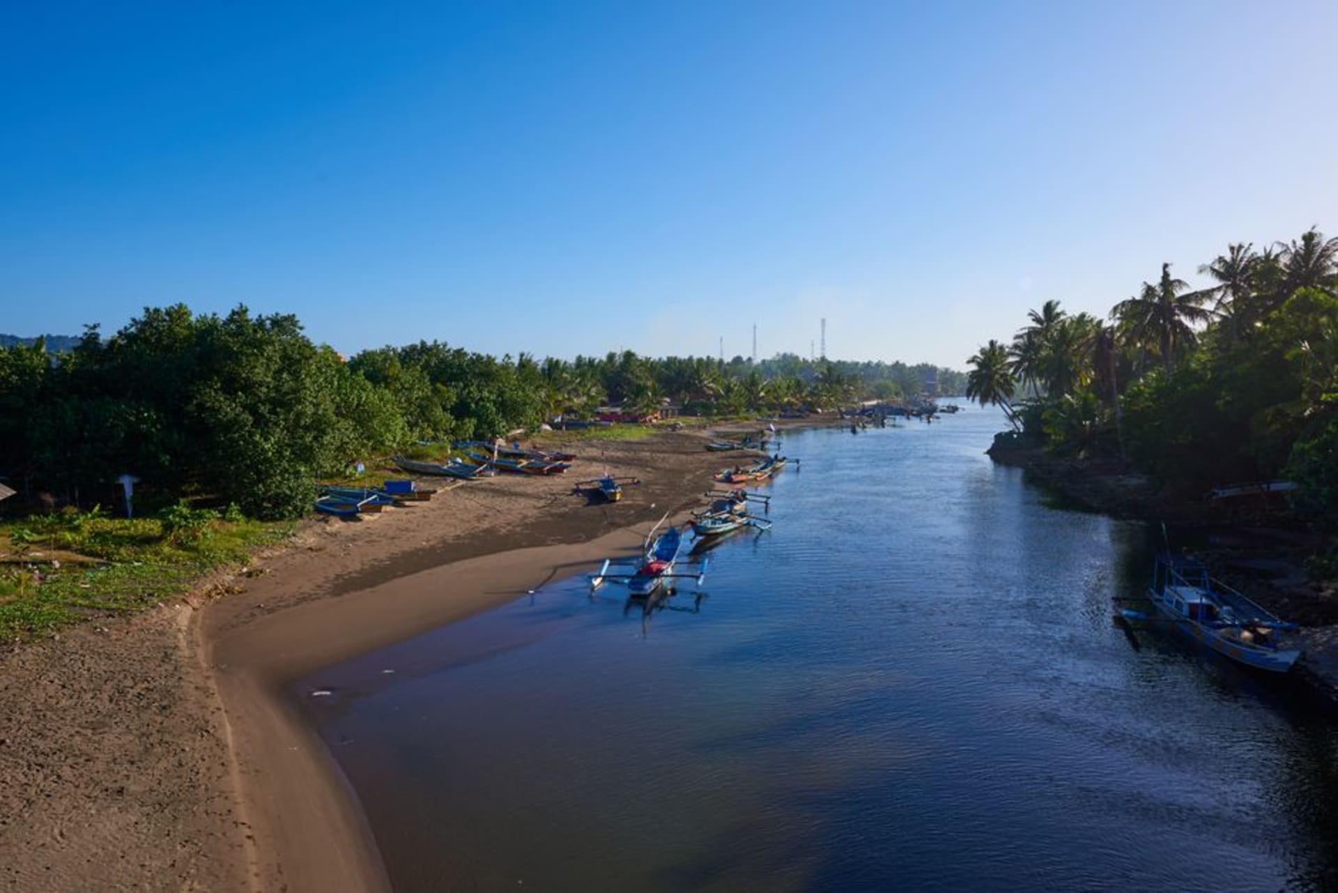 Black volcanic sand beach at Lovina with traditional outrigger fishing boats at sunrise