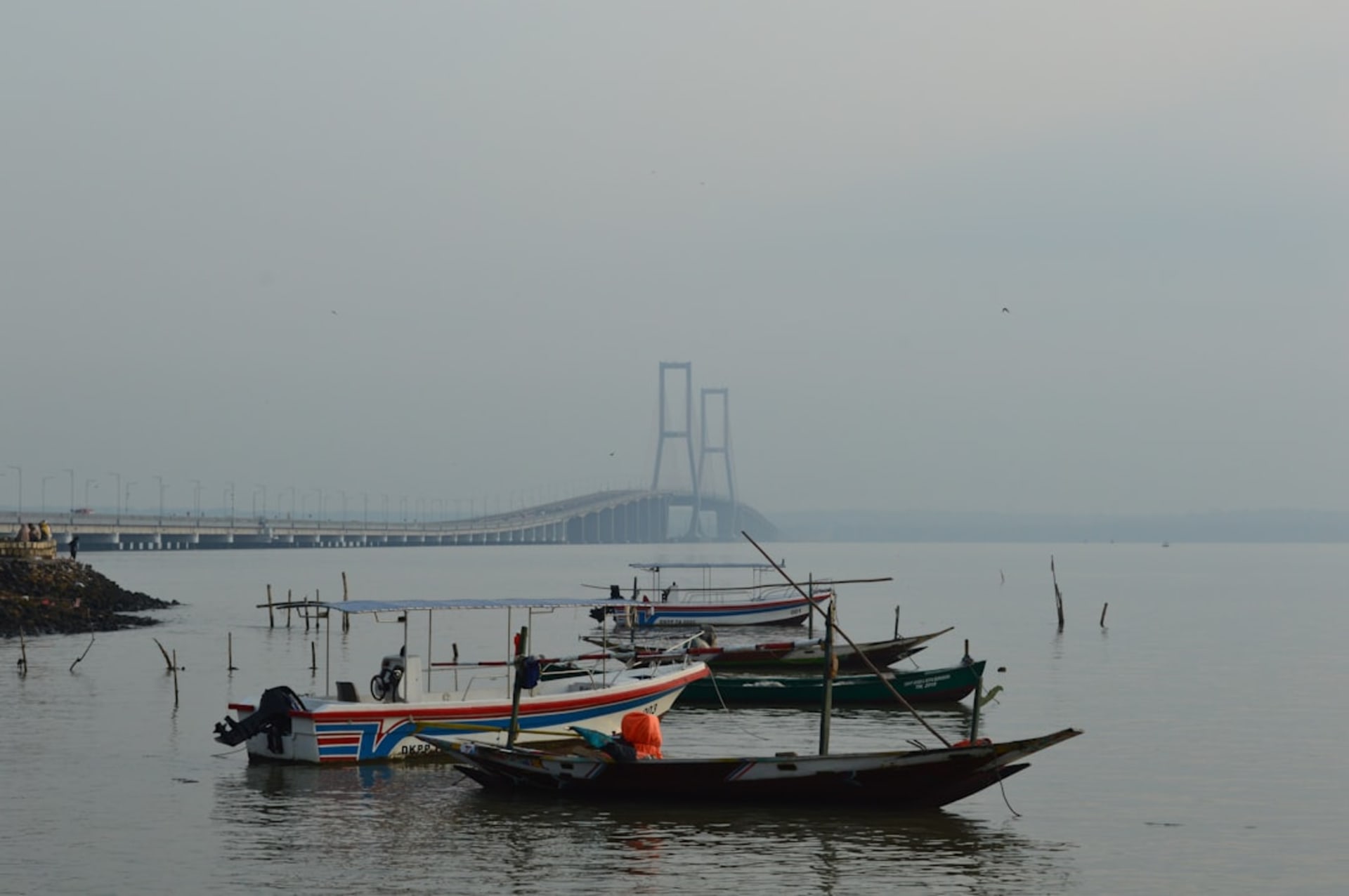 Surabaya harbor at dusk with cargo ships and the city skyline beyond