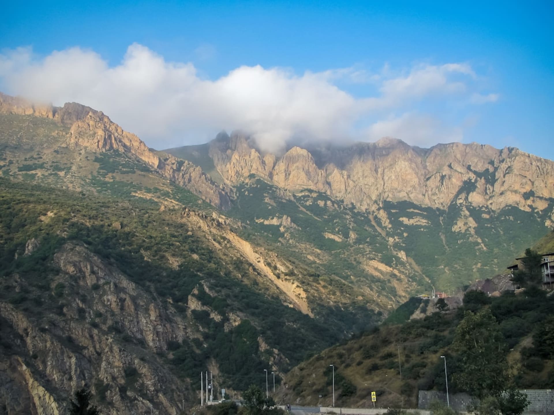 The Chalus Road winding through steep green Alborz mountain terrain with tunnels and switchbacks visible ahead