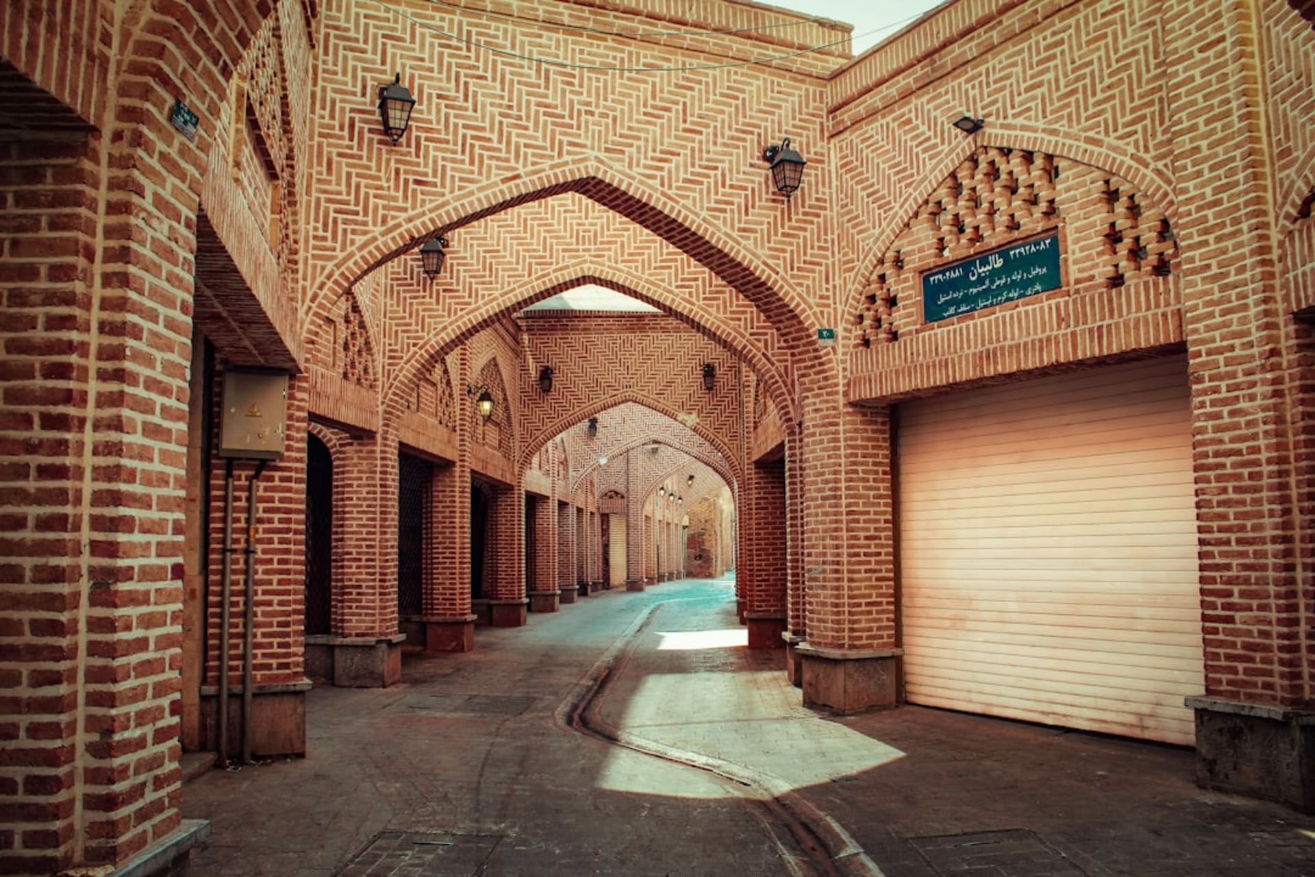 La façade carrelée ornée et le balcon en bois sculpté du palais de Hasht Behesht, niché parmi de grands arbres dans son jardin