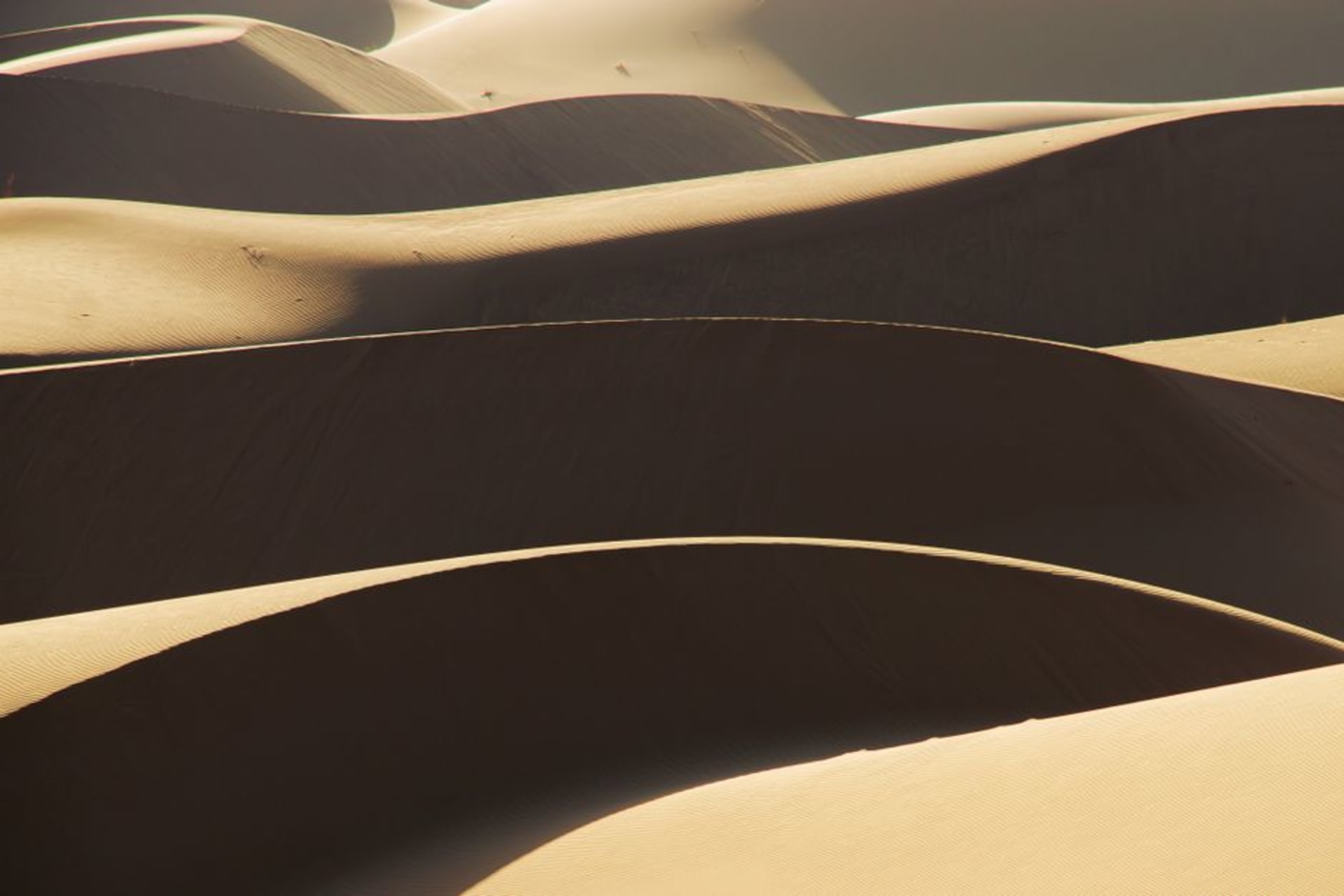 Dunas de arena doradas del desierto de Maranjab al atardecer con un viejo caravasar de piedra visible a lo lejos
