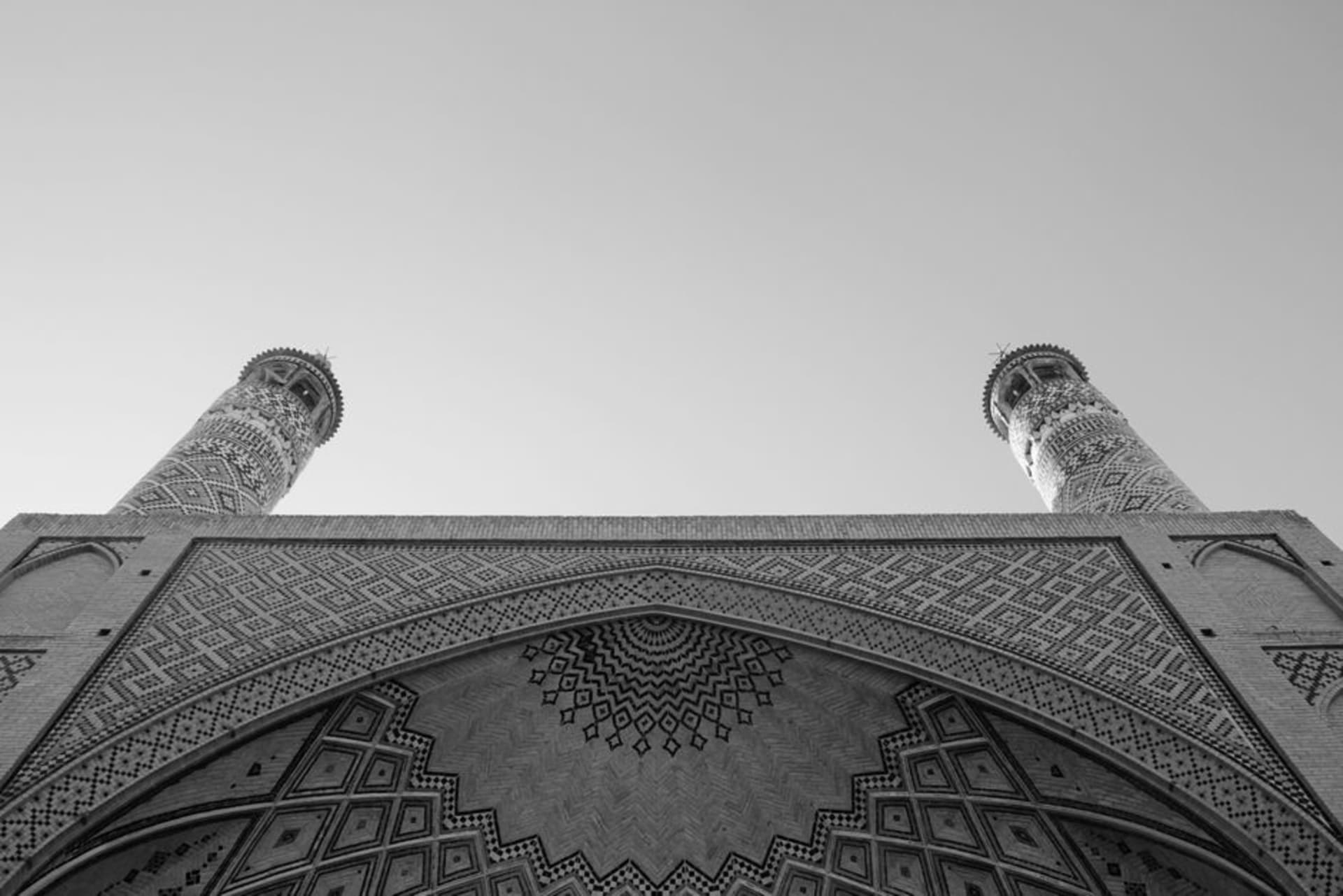 The twin blue-tiled minarets of Monar Jonban rising above a small brick mausoleum courtyard on the outskirts of Isfahan