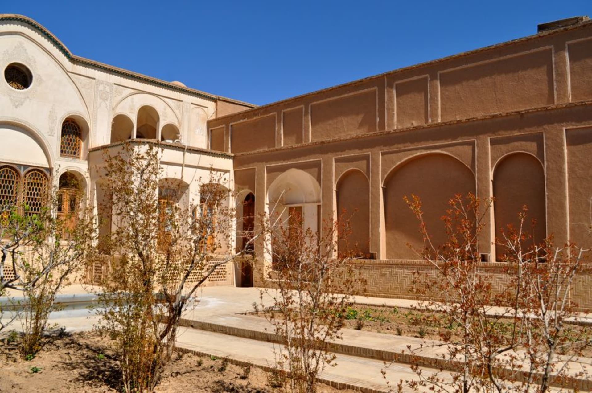 Ornate stucco archway and colored stained-glass windows inside the courtyard of Tabatabaei House in Kashan