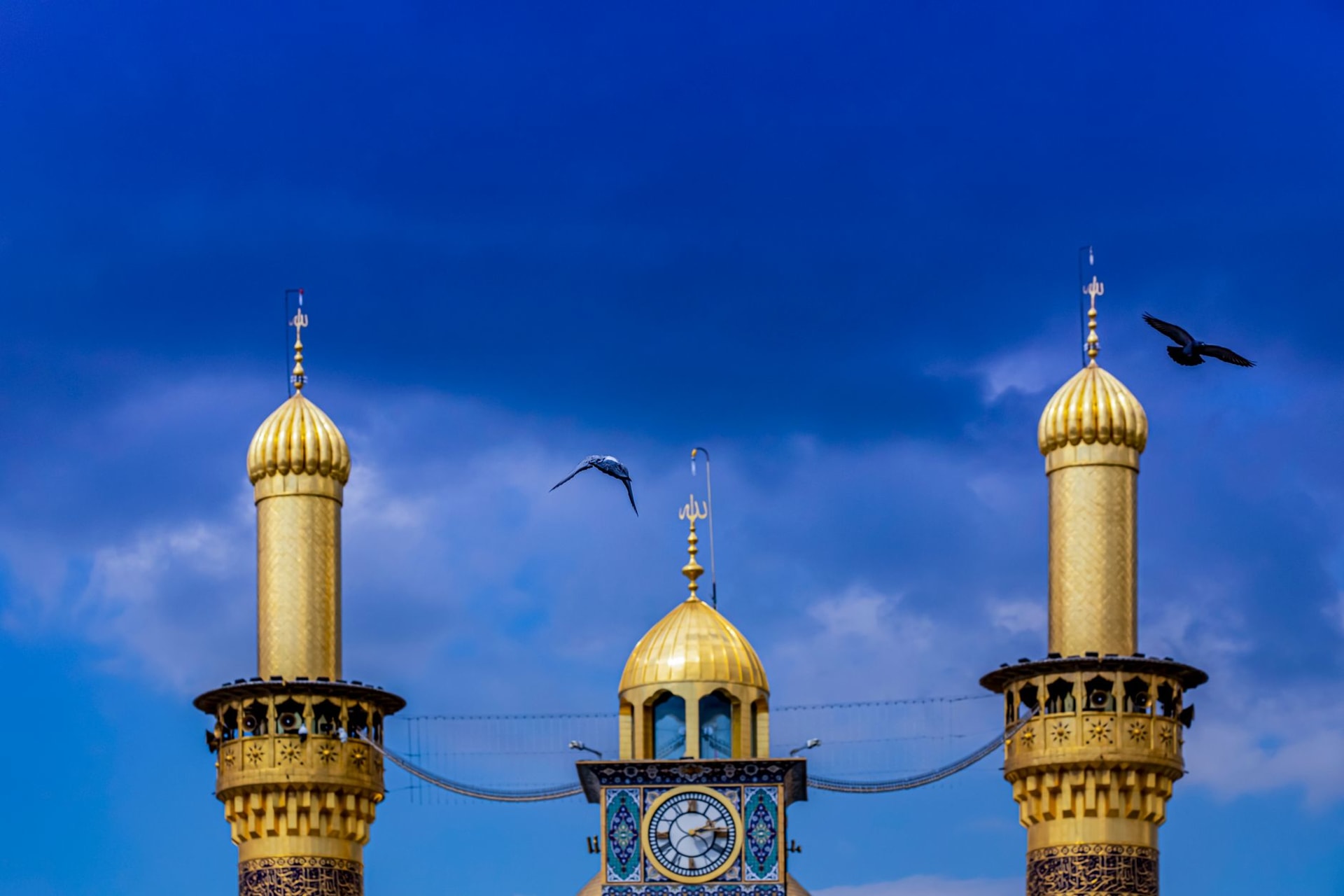 Las dos cúpulas doradas de los santuarios del Imán Husayn y Abbas en Kerbala elevándose sobre la ciudad desértica, iluminadas de noche contra un cielo oscuro