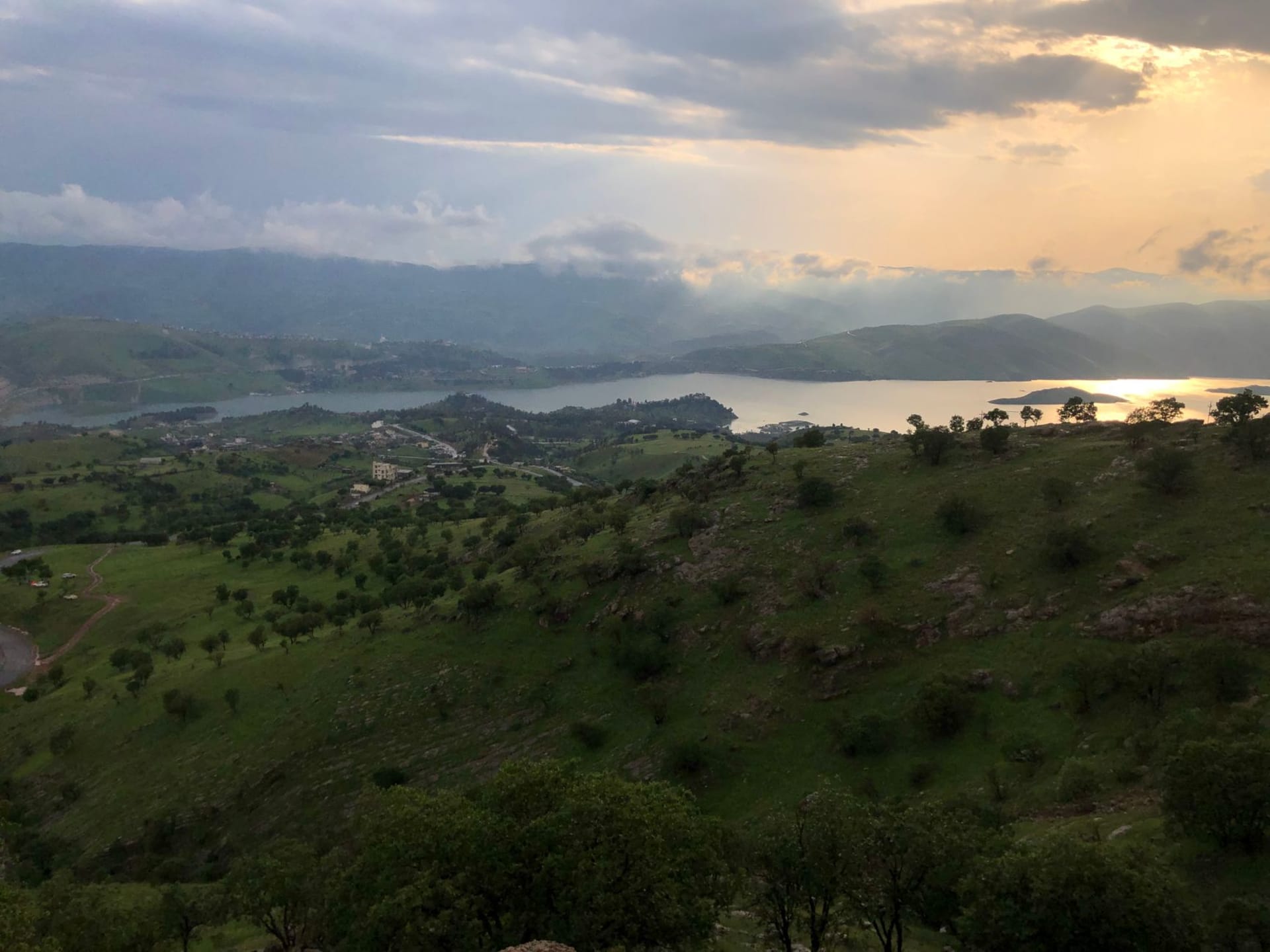 Sulaymaniyah's hillside skyline with the Azmar mountain range rising in the background, the city's rooftops scattered across the valley in soft afternoon light