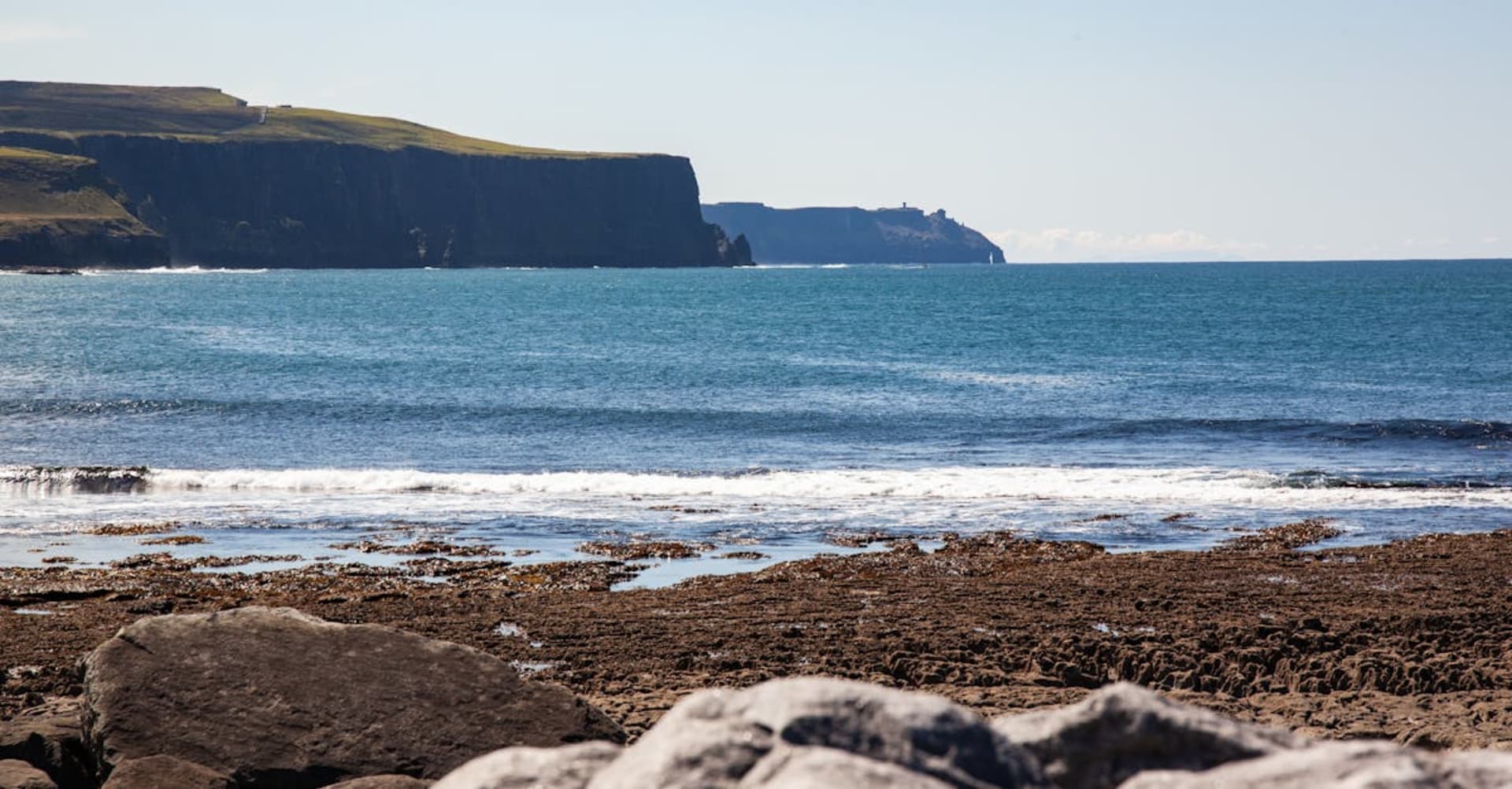 The Cliffs of Moher rising dramatically above the Atlantic Ocean with waves crashing below
