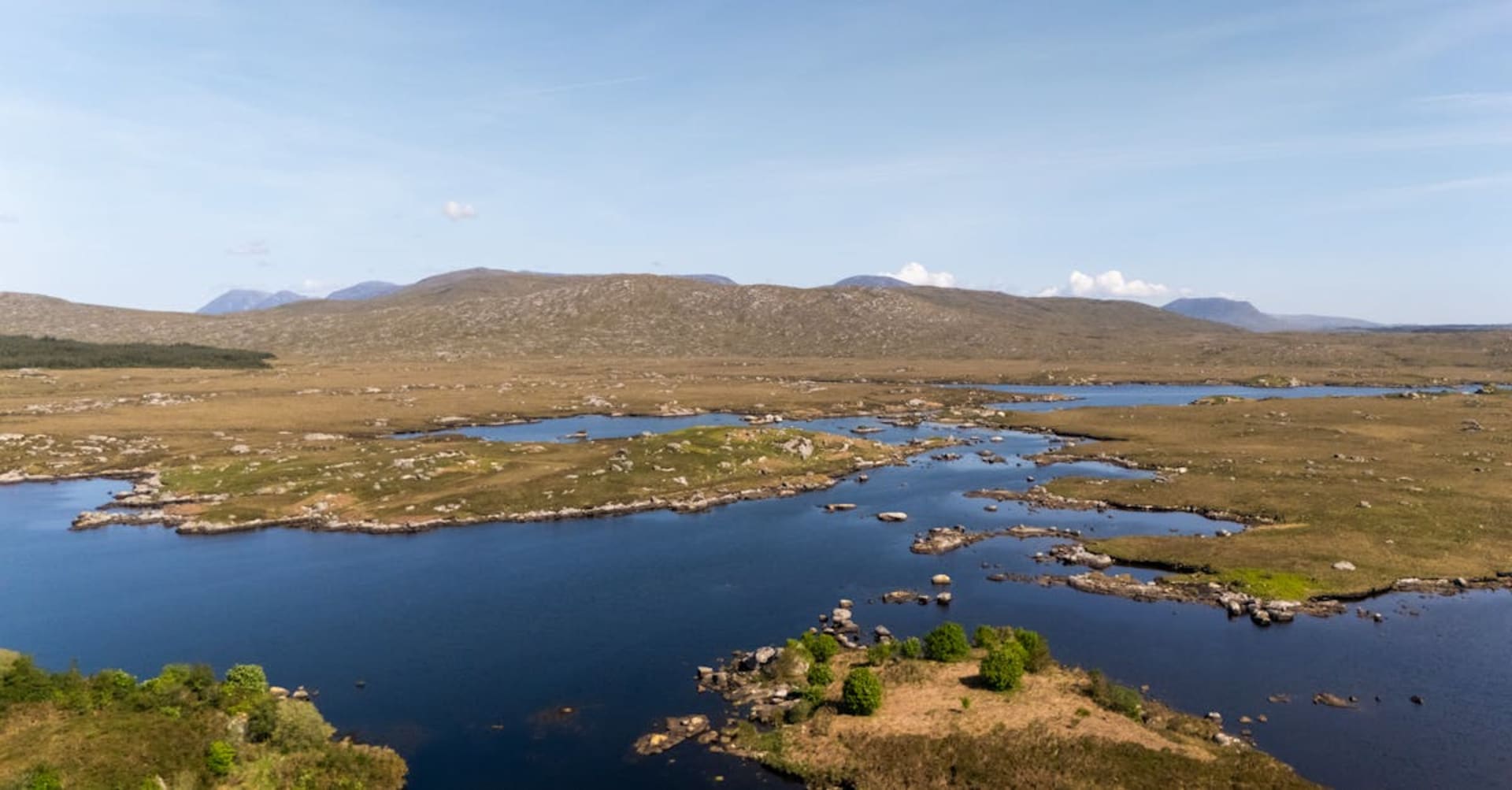 Connemara ponies grazing beside a still lake with the Twelve Bens mountain range reflected in the water