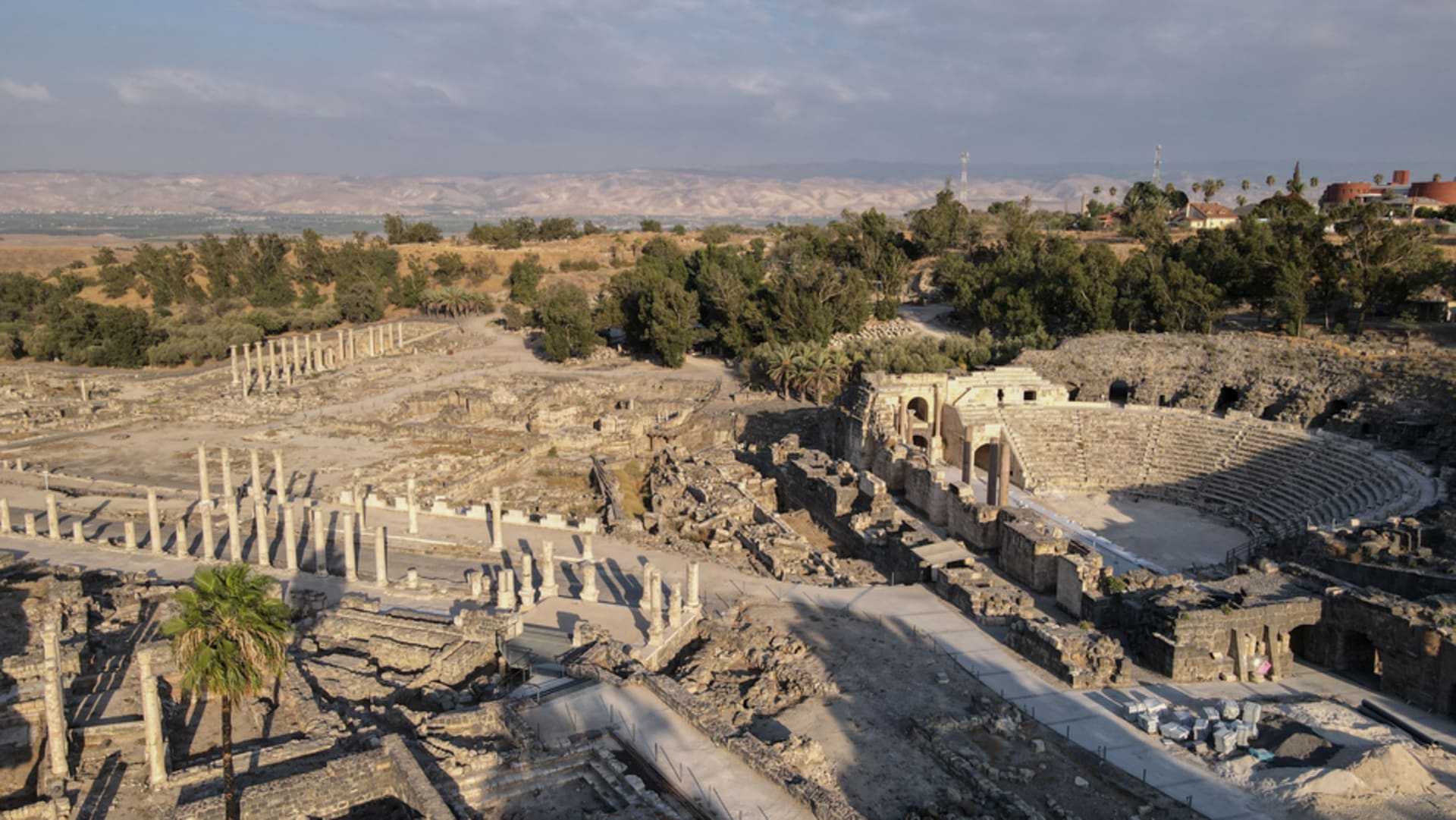 Roman columns lining the ancient main street of Beit She'an with the theater visible in the background under bright daylight