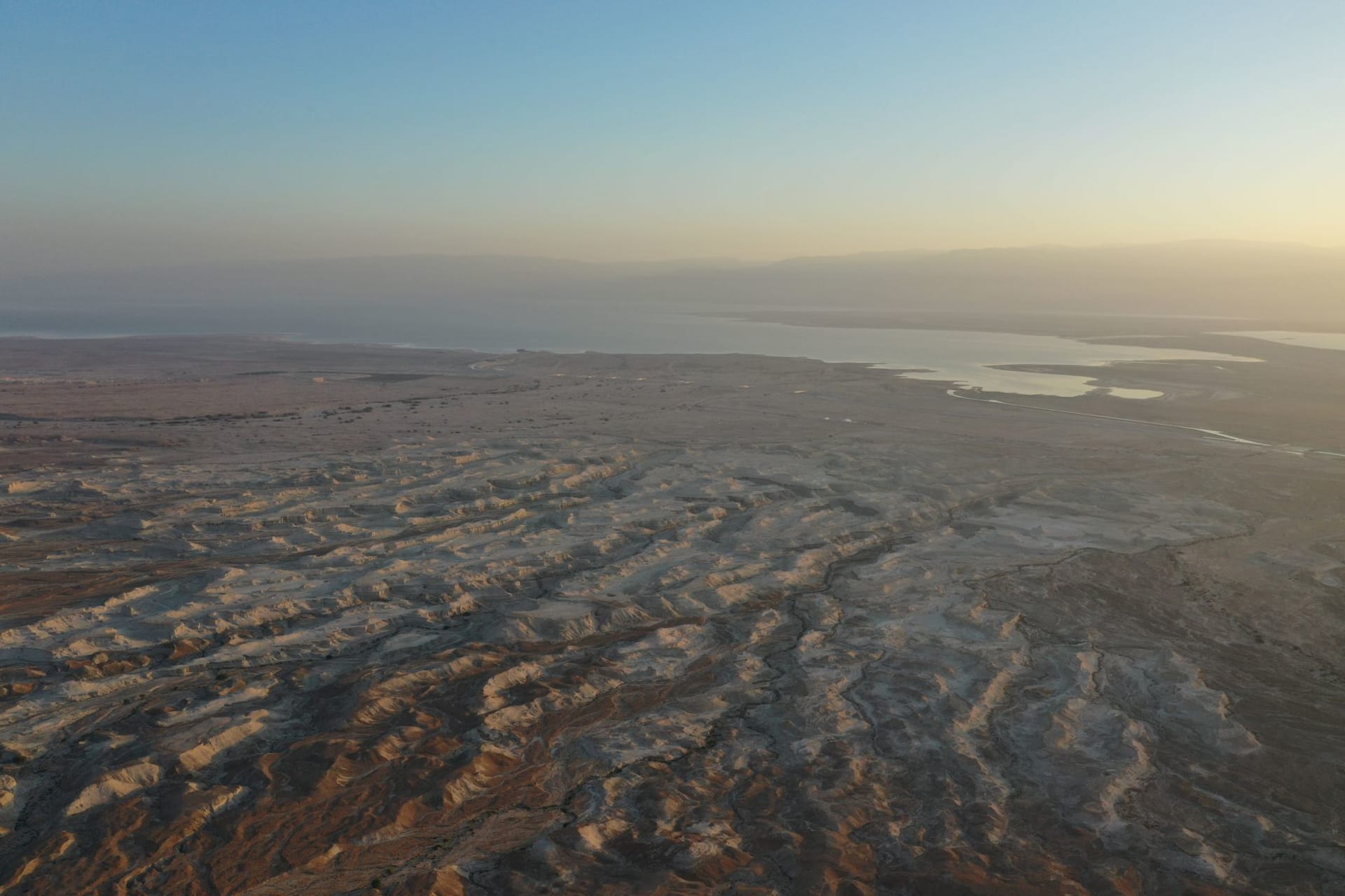 Una persona flotando sin esfuerzo sobre el Mar Muerto, de un azul imposible y cristalino, contra un telón de fondo de acantilados ocres del desierto de Judea