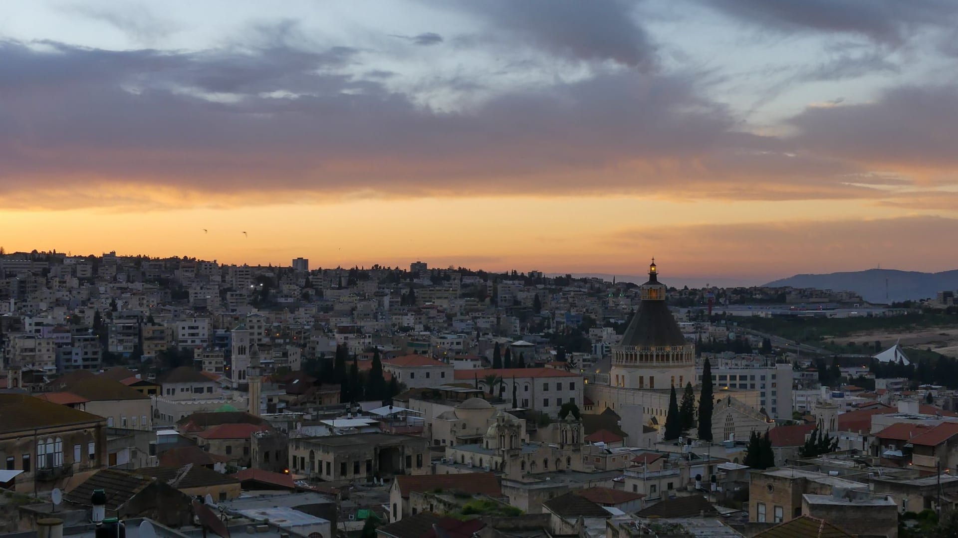 The white dome and bell tower of the Basilica of the Annunciation rising above the tight rooftops of Nazareth's old city, morning light catching the stone