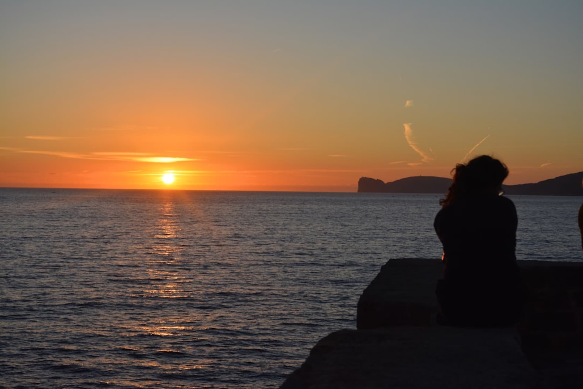Alghero's stone ramparts and bastions glowing at sunset over the sea