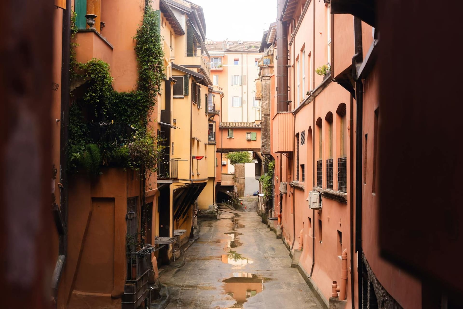 A long shaded portico in Bologna with terracotta arches receding into the distance and warm afternoon light on the brick walls