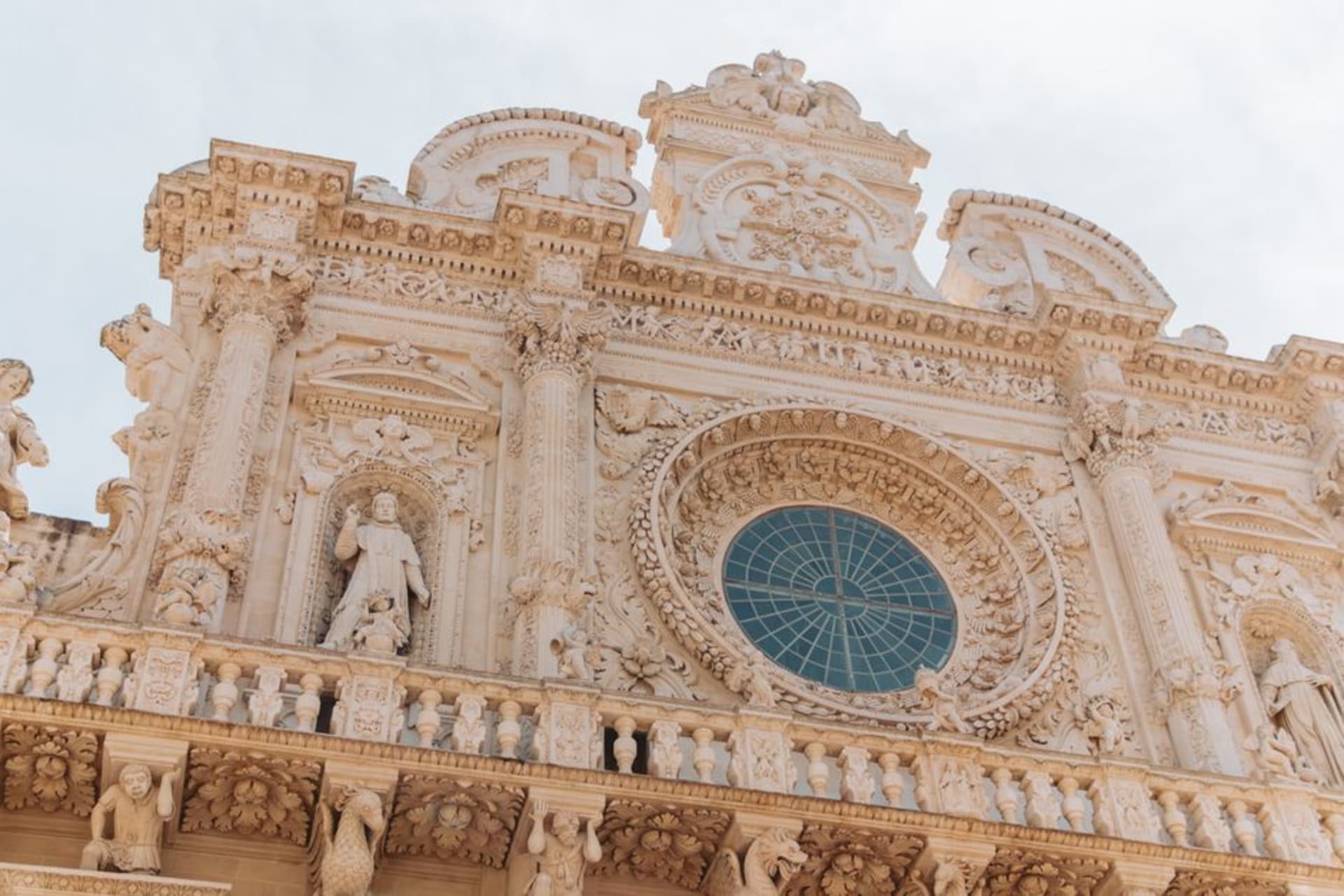 The ornate Baroque facade of Lecce's Basilica di Santa Croce carved from golden Pietra Leccese limestone
