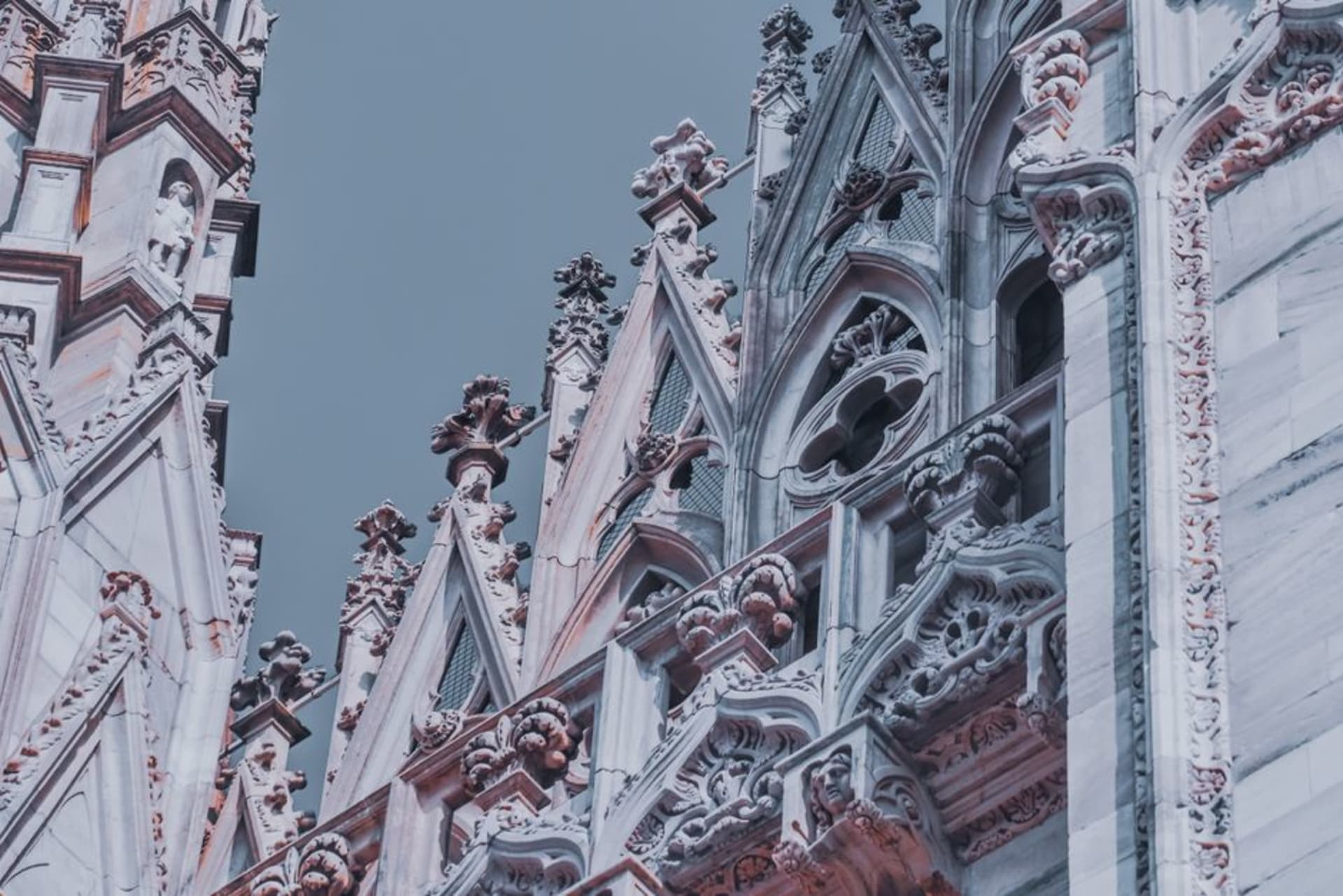 The white marble spires of Milan's Duomo against a clear sky