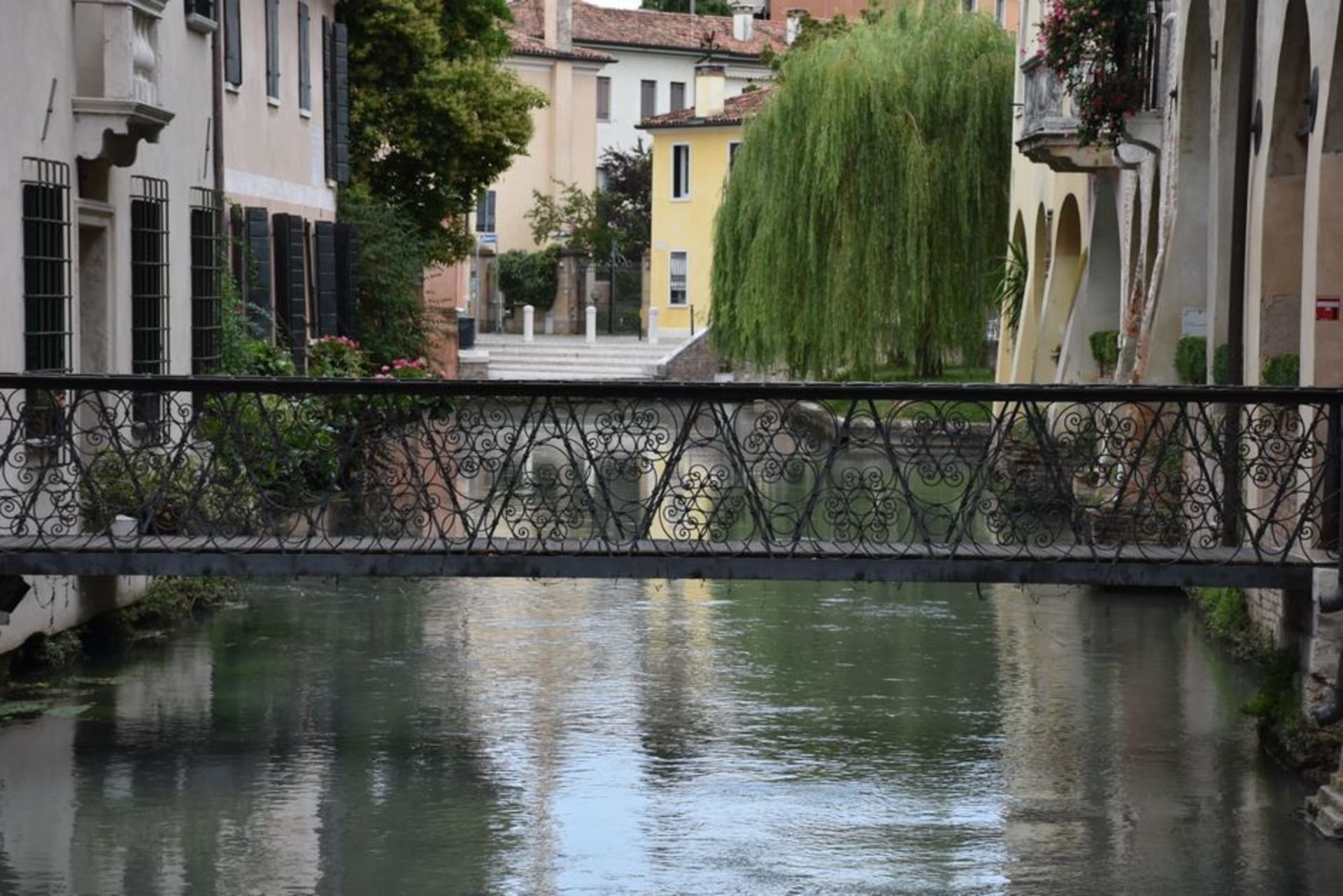 A narrow canal in Treviso lined with pastel-colored houses and arched bridges