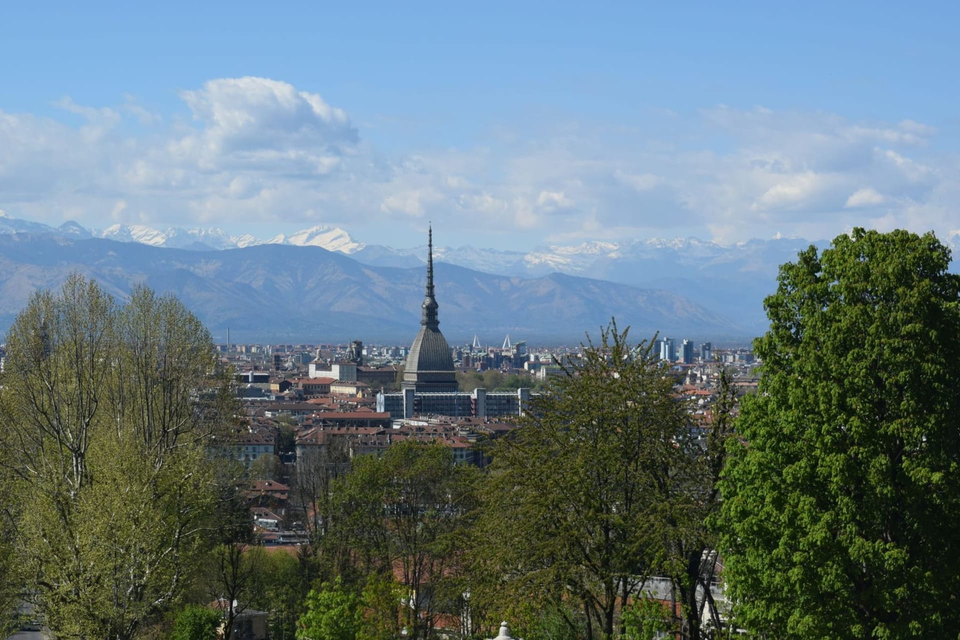The Mole Antonelliana rising above Torino's terracotta rooftops with snow-capped Alps stretching across the horizon at golden hour