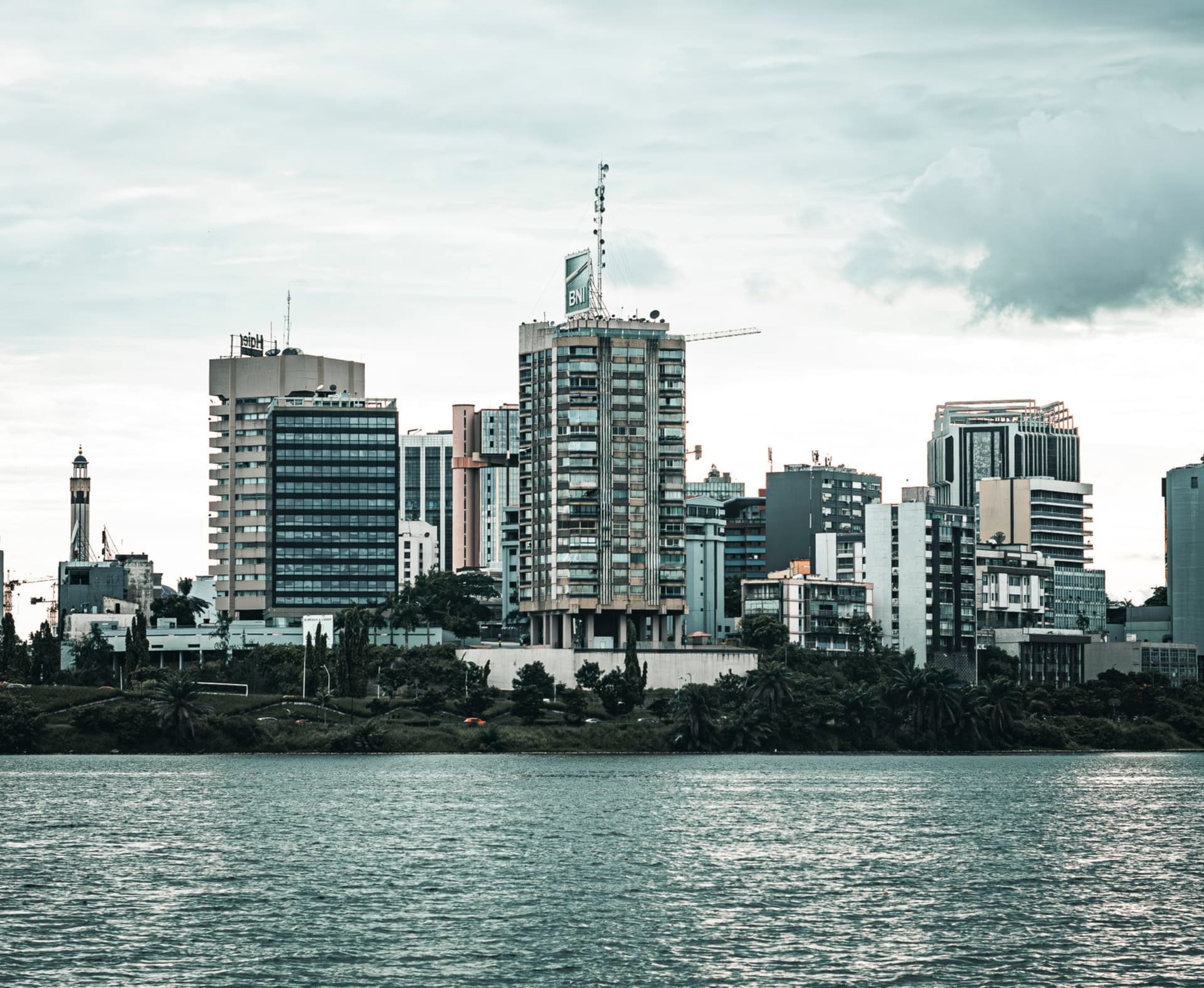 Contemporary cityscape of Abidjan with high-rise towers reflected in the lagoon under overcast skies, photo by Jean Marc Bonnel