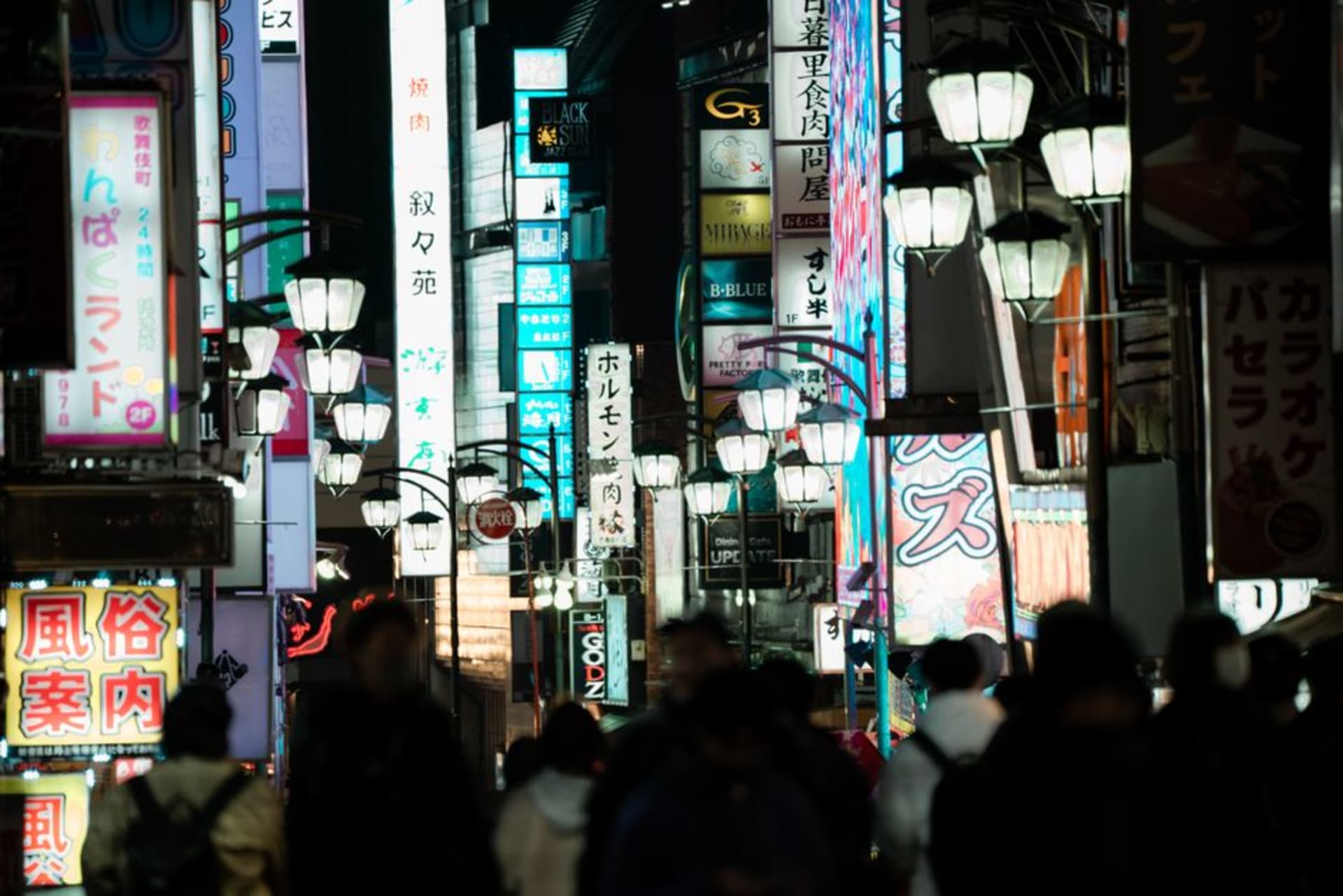 Performers balancing tall bamboo poles hung with paper lanterns against the night sky during Akita's Kantō festival