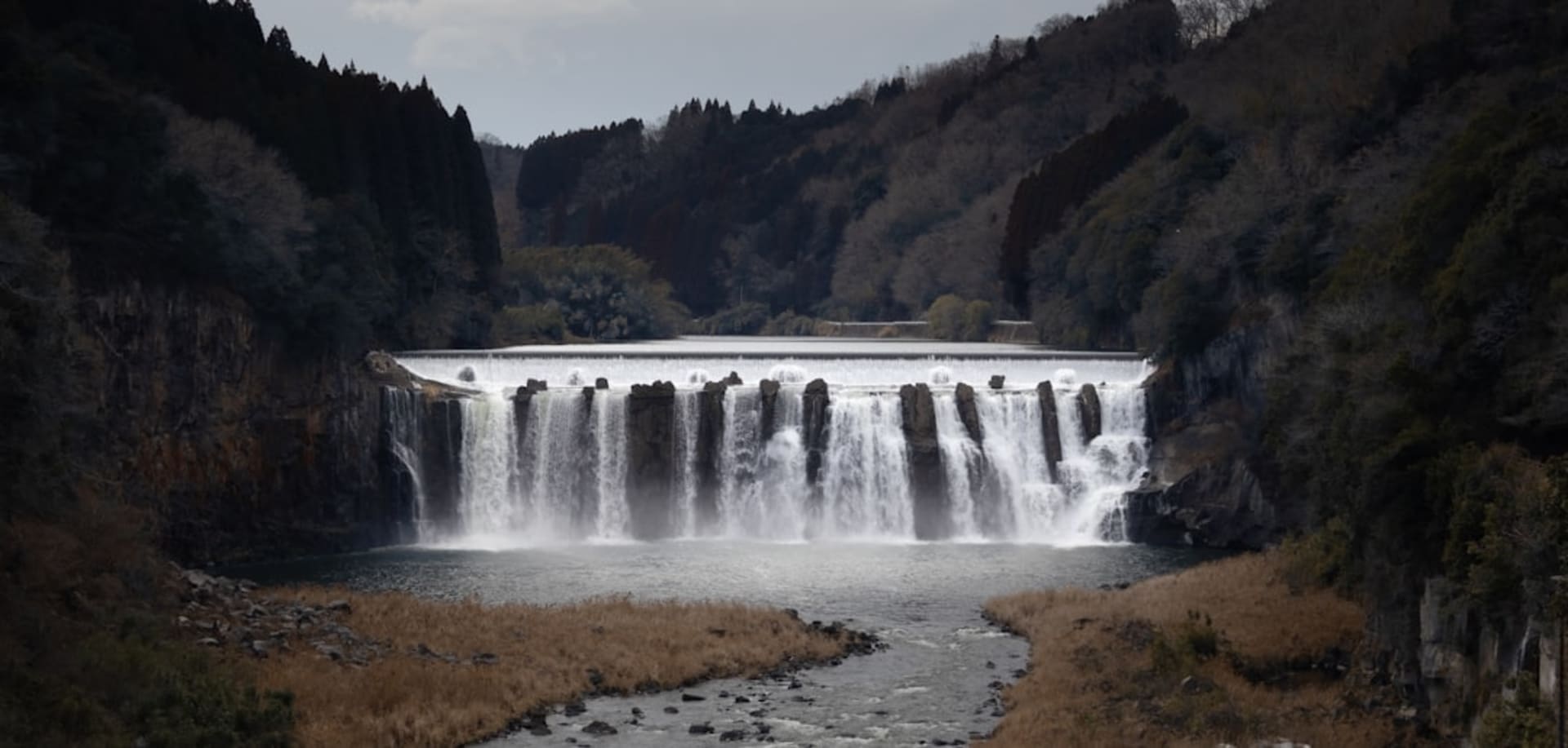 The Enakyō gorge near Ena, sheer sculpted cliffs rising from green river water with autumn colour on the slopes