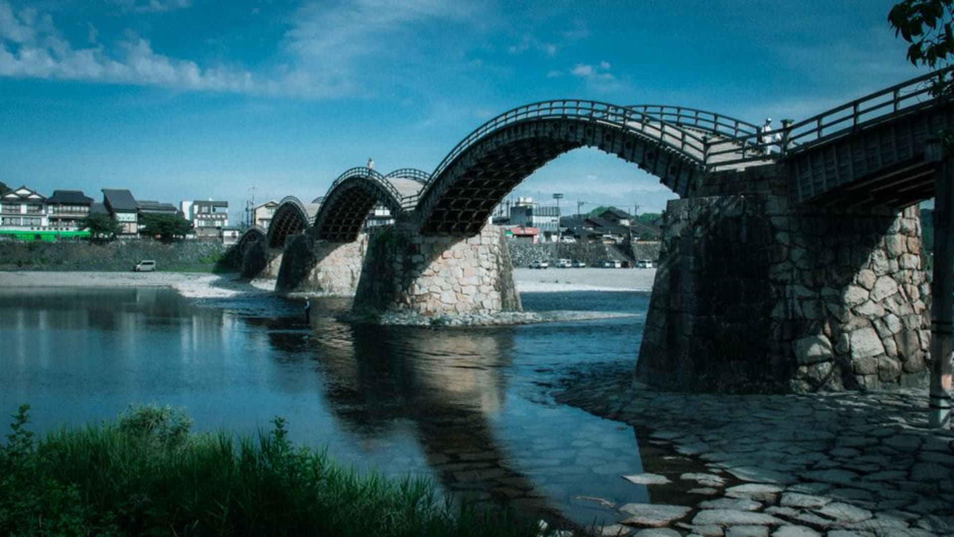 The five wooden arches of the Kintaikyo bridge spanning the Nishiki river at Iwakuni with the hilltop castle behind