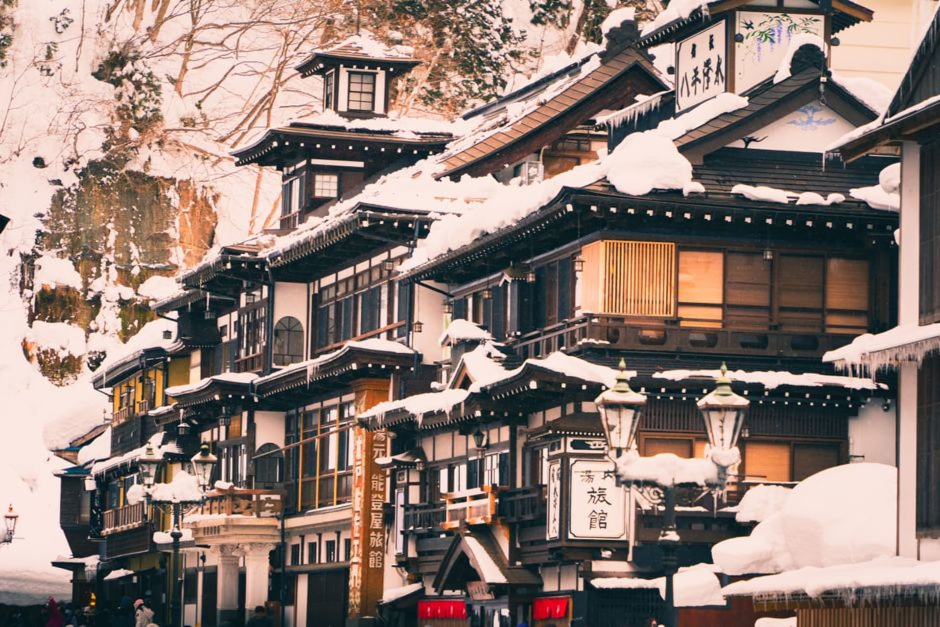 Wooden ryokan buildings stacked along a wooded river gorge in Kurokawa Onsen, steam drifting up between them
