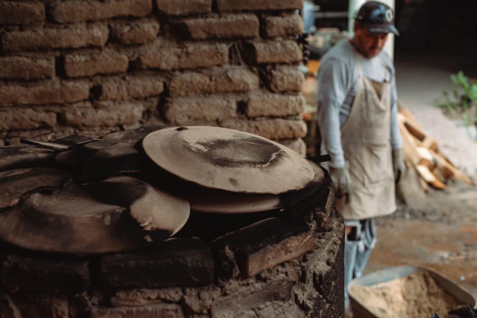 Rustic brown and cream Mashiko-ware bowls arranged on a wooden shelf outside a kiln