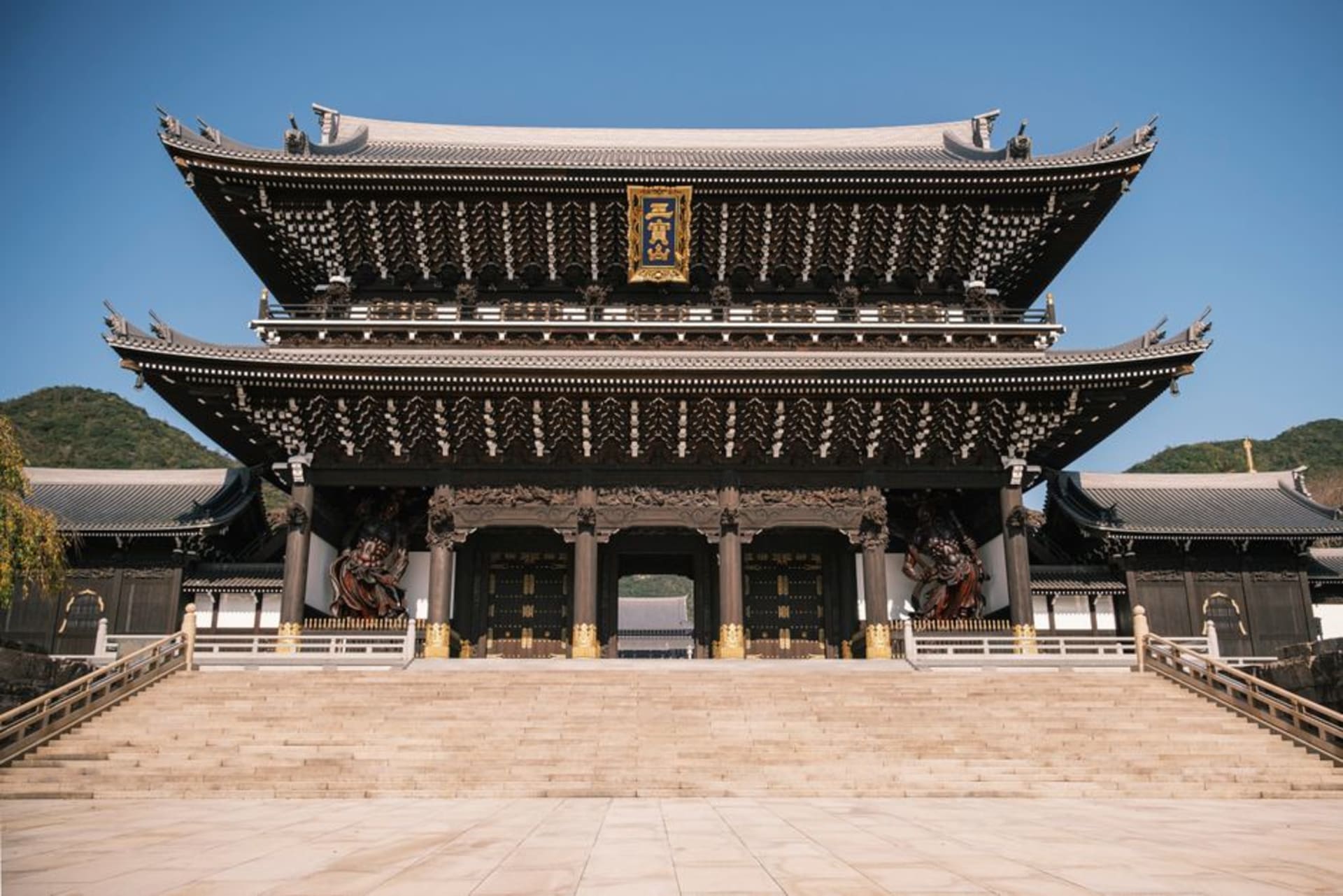 The main hall of Naritasan Shinshoji temple with its multi-tiered pagoda rising behind, pilgrims crossing the wide stone courtyard
