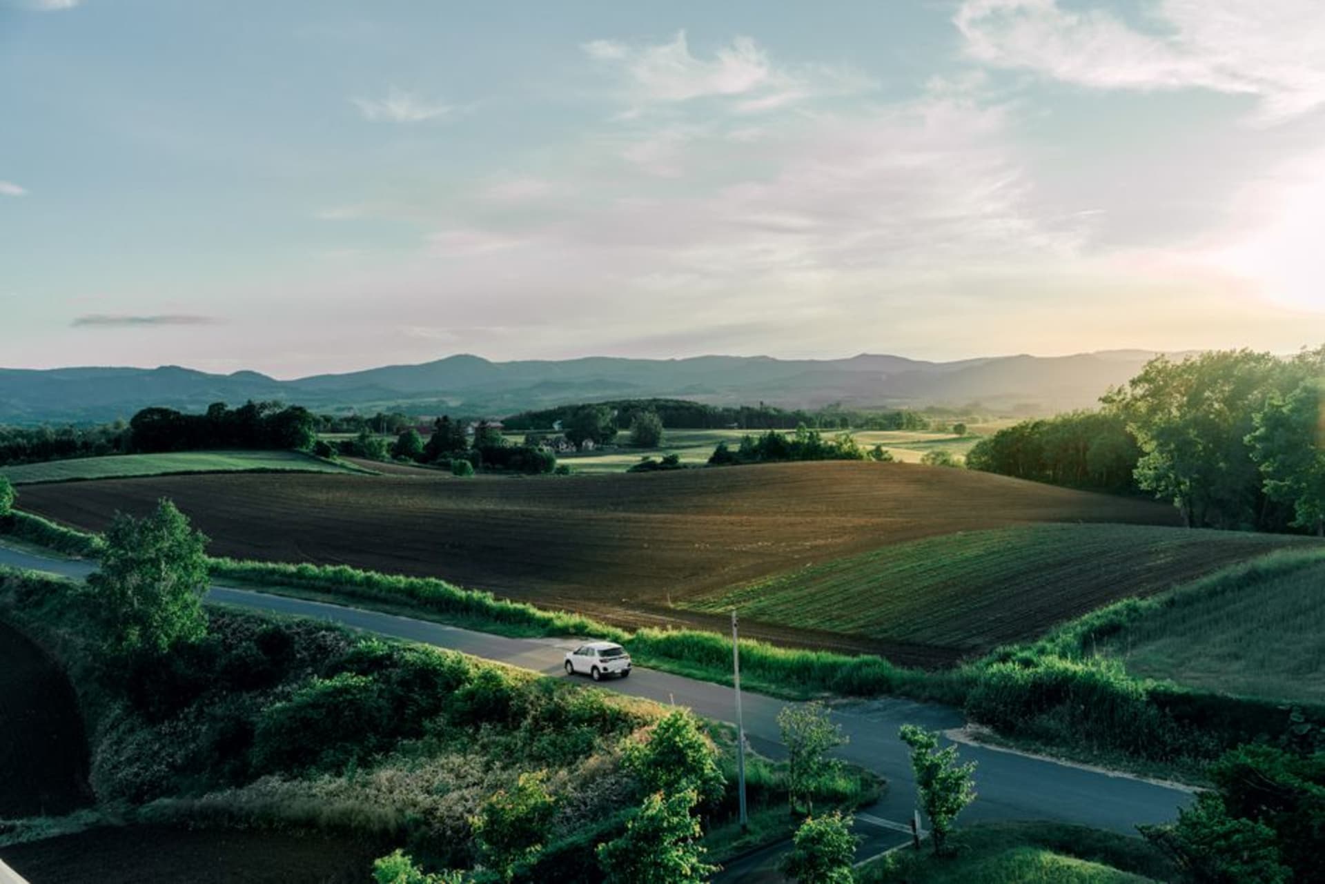 The wide flat farmland of the Tokachi plain around Obihiro, cultivated fields stretching to distant hills under a huge sky