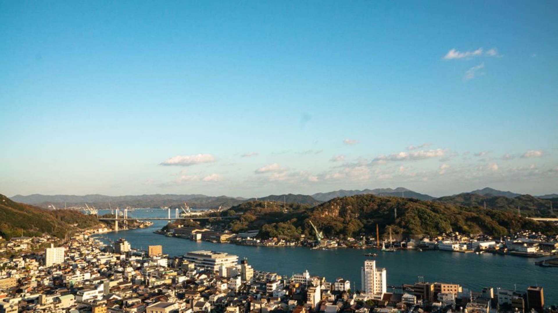 The hillside town of Onomichi tumbling down to the narrow Inland Sea strait, temple roofs among the houses, ships and islands beyond