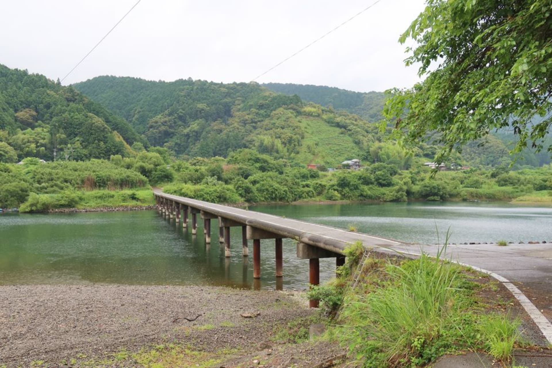 The wide green Shimanto River winding through forested hills under a soft sky