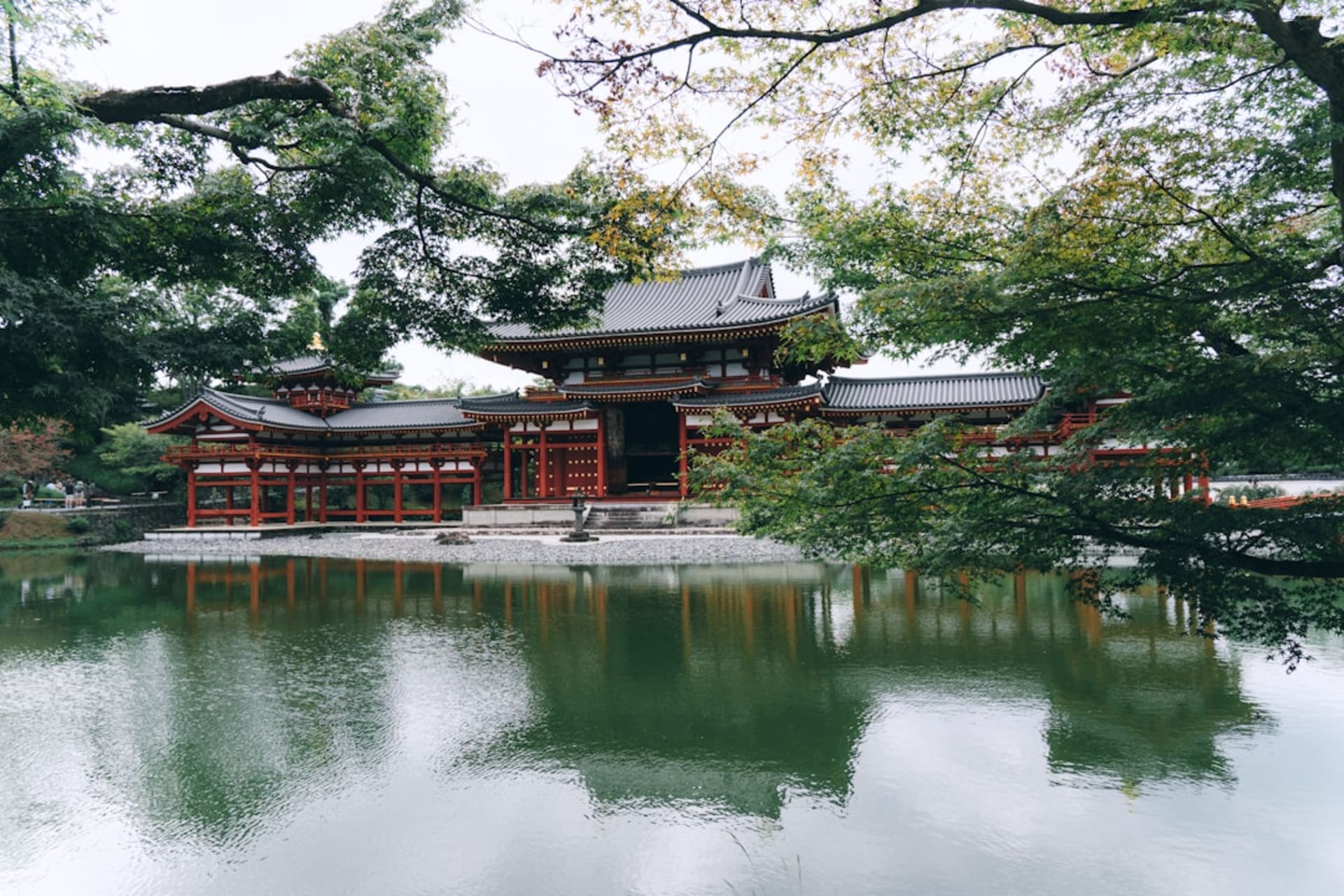 The Byōdō-in Phoenix Hall reflected in its pond in Uji, symmetrical wooden wings spread wide against green hills