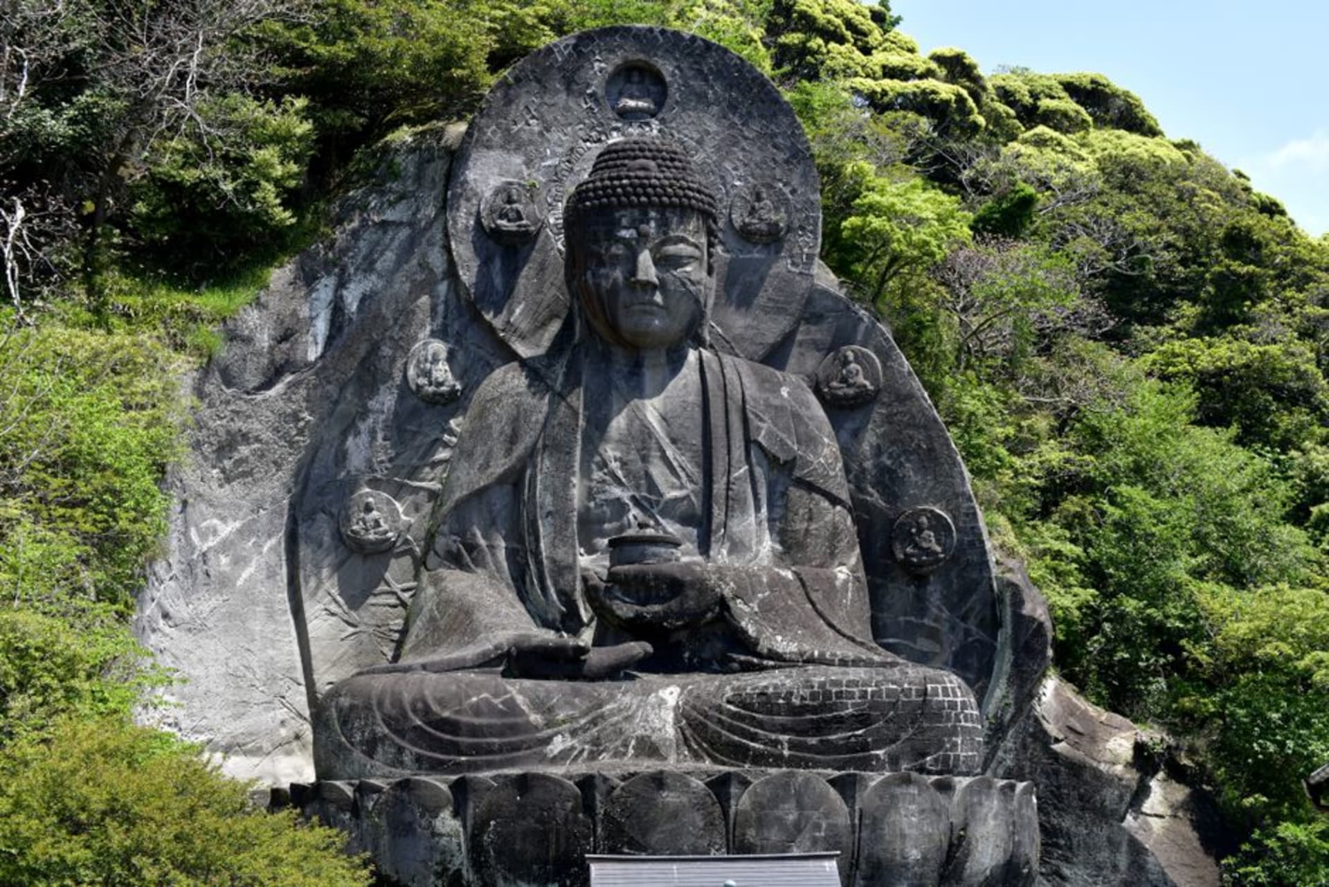 Weathered stone Buddha statues carved into a cliff face at Usuki