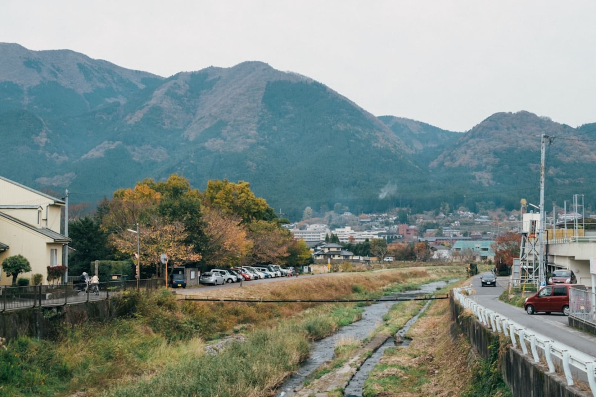 The twin peaks of Mount Yufu rising above the green fields and rooftops of Yufuin in morning mist