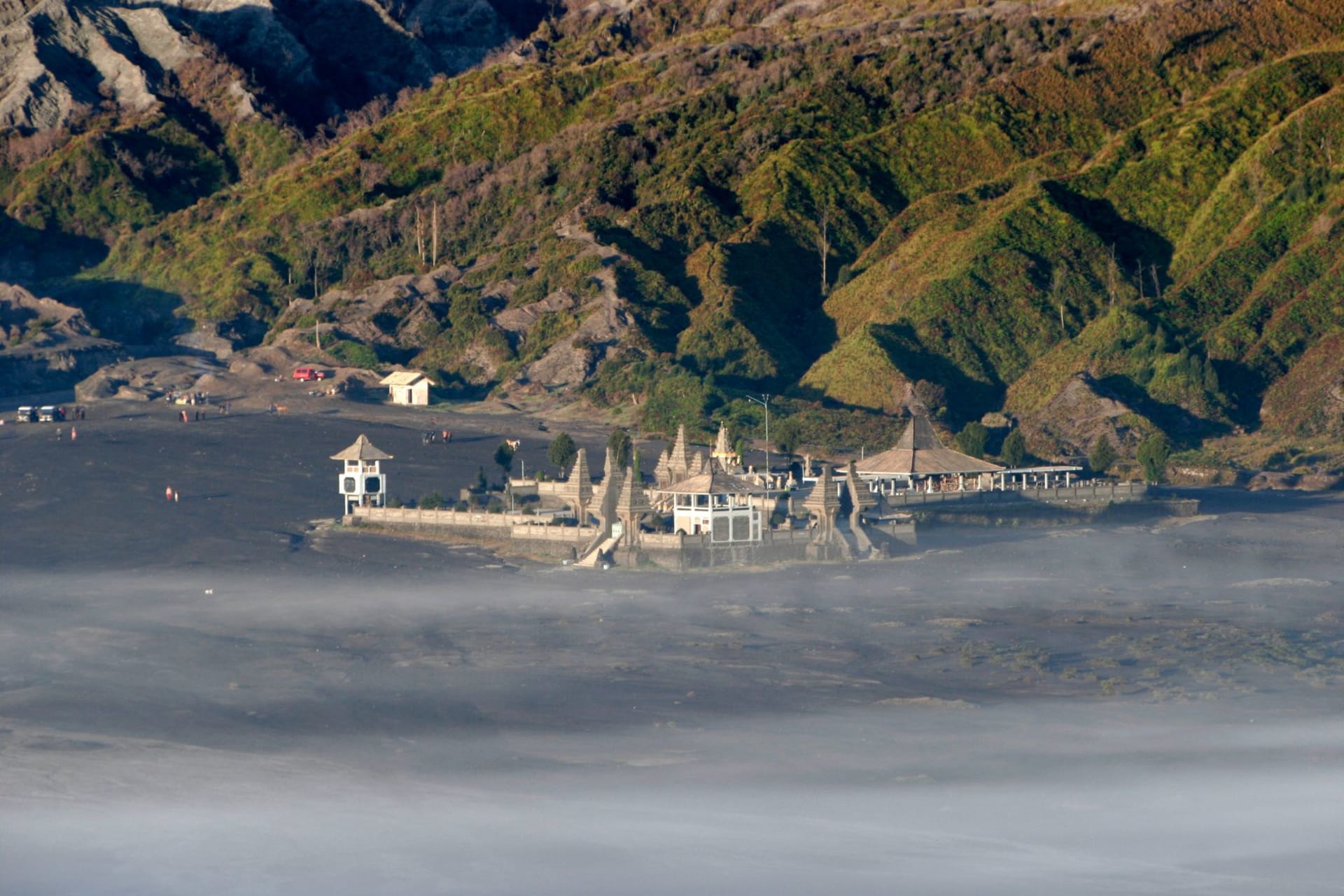 Ancient Hindu temple compound at the base of Mount Bromo volcano surrounded by lush tropical greenery, Java, Indonesia