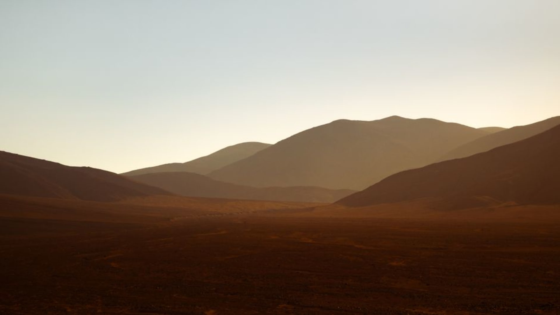 The rust-colored slopes of Tsodilo Hills catching late afternoon light above the flat Kalahari sand