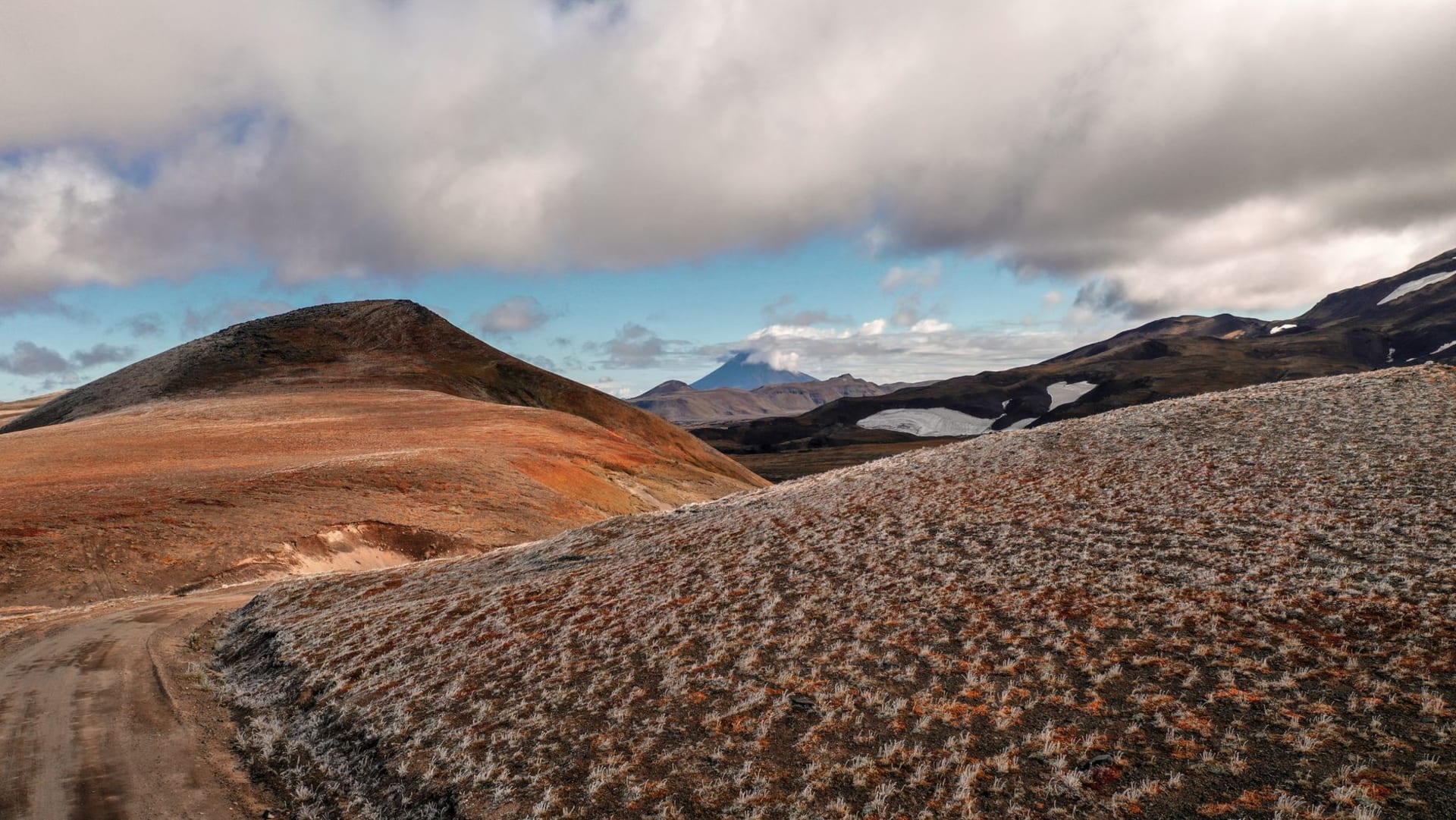 El pueblo de Esso en el interior de Kamchatka, casas de madera dispersas por un valle fluvial con taiga de abedules que asciende hasta la tundra abierta y montañas más allá