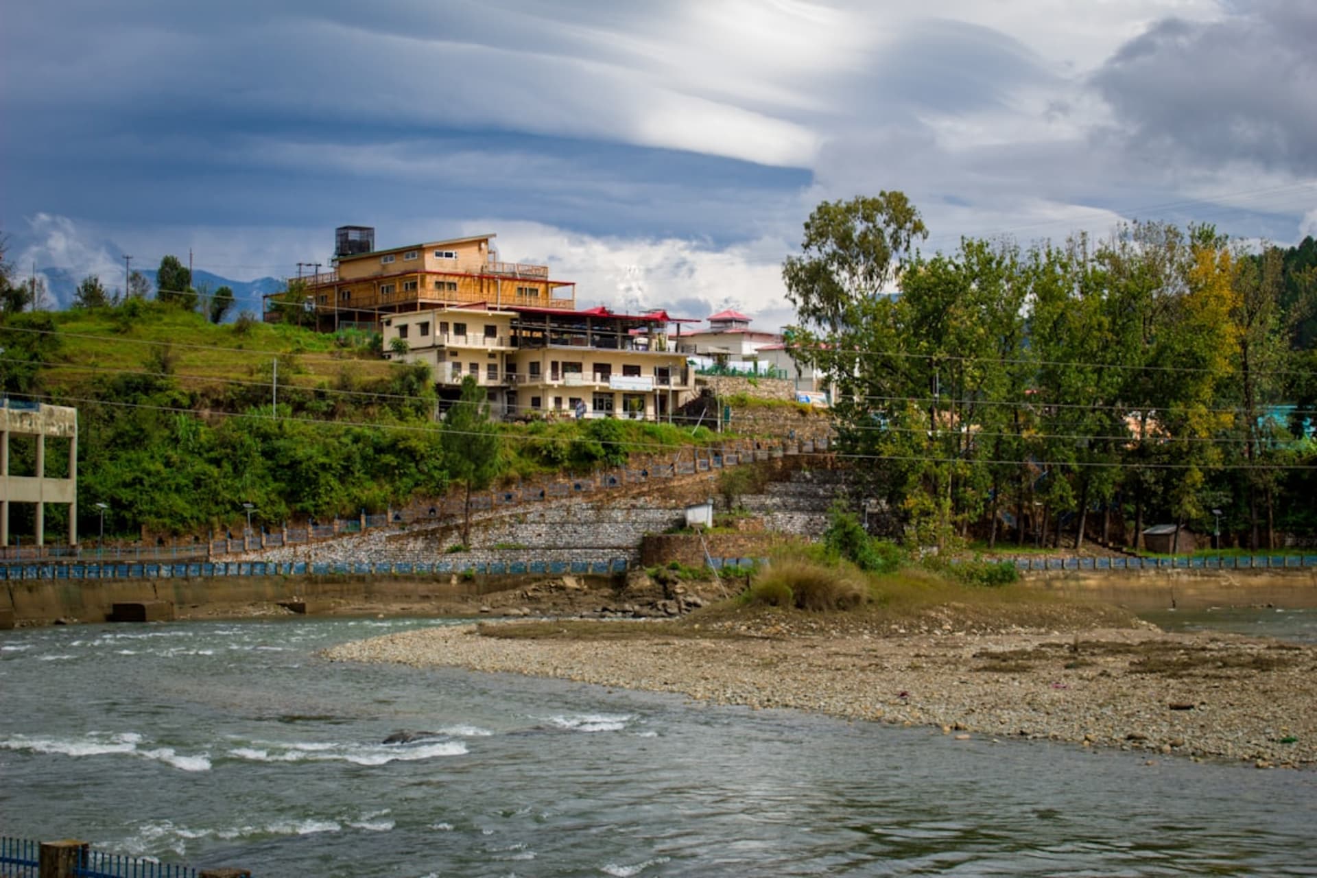 El río Jhelum fluyendo por Baramulla con un antiguo puente de hierro y casas ribereñas a lo largo de la orilla