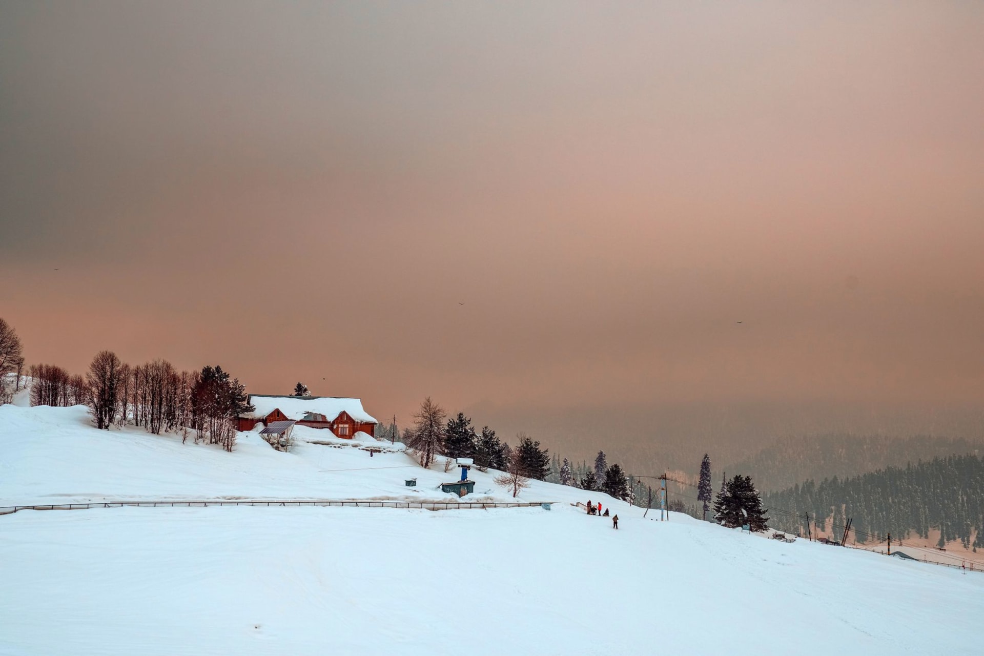 The snow-covered bowl of Gulmarg at winter with skiers on open slopes and the Apharwat ridge towering above