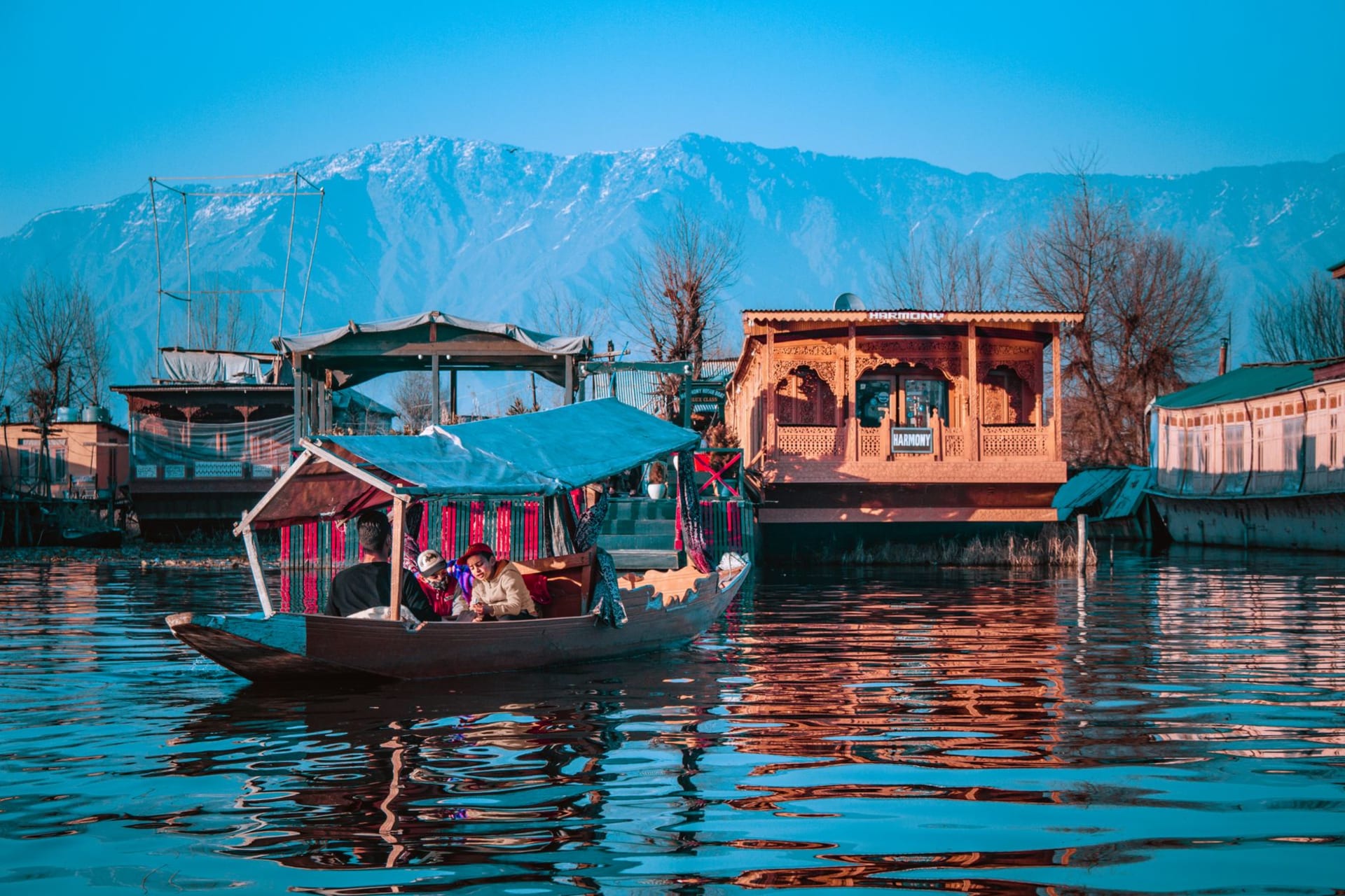 A group enjoying a Shikara ride on Dal Lake with the Himalayan mountains reflected in the still water, Srinagar
