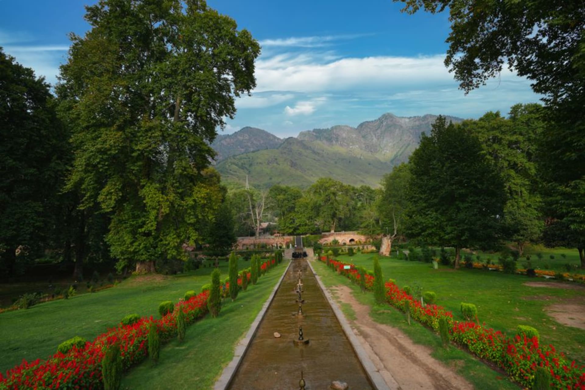 Céspedes escalonados y albercas de manantial cristalinas en el jardín de Kokernag con nogales bordeando los senderos