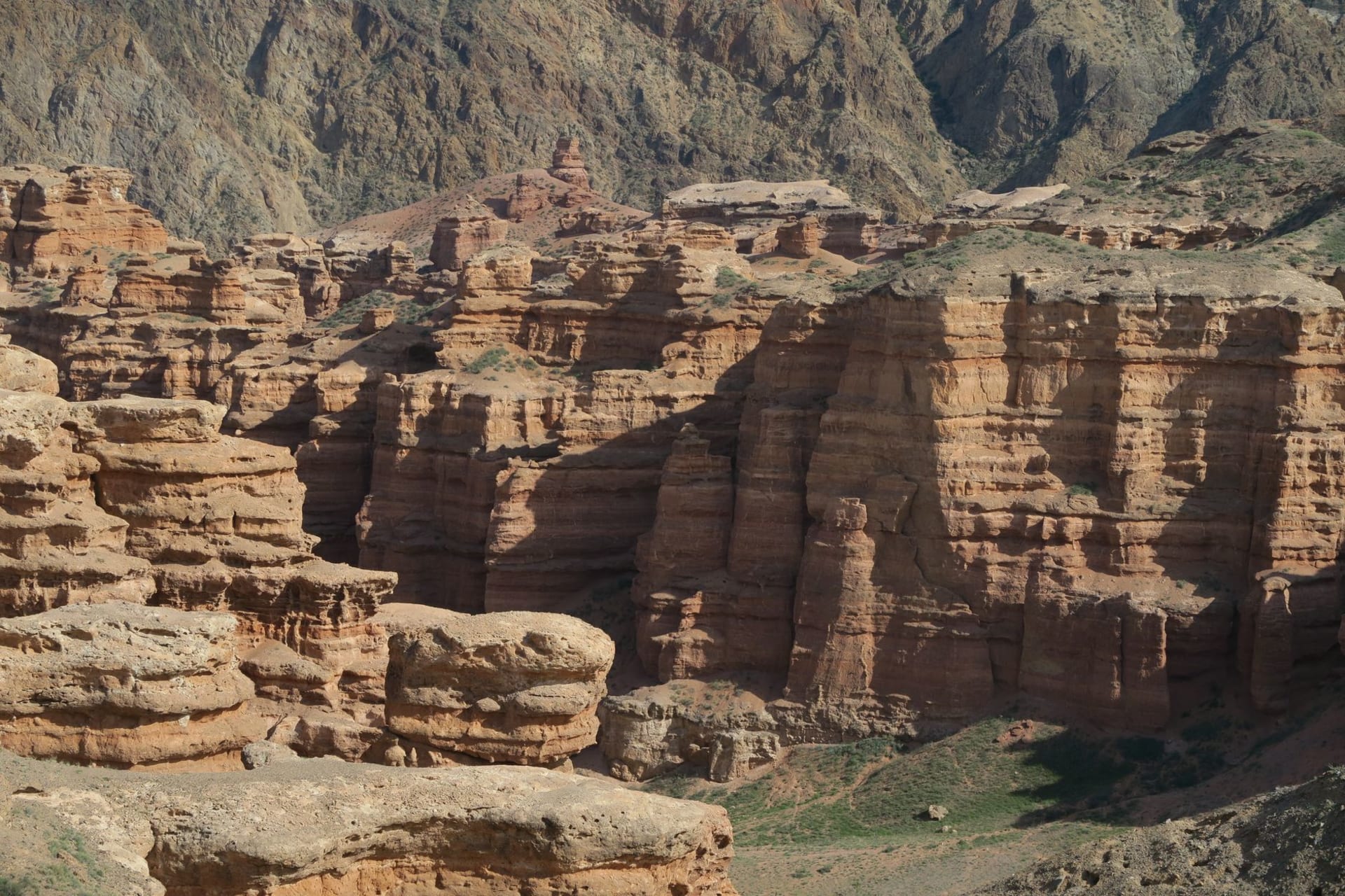 Towering rust-red and orange rock formations of Charyn Canyon's Valley of Castles bathed in the sharp light of late afternoon sun