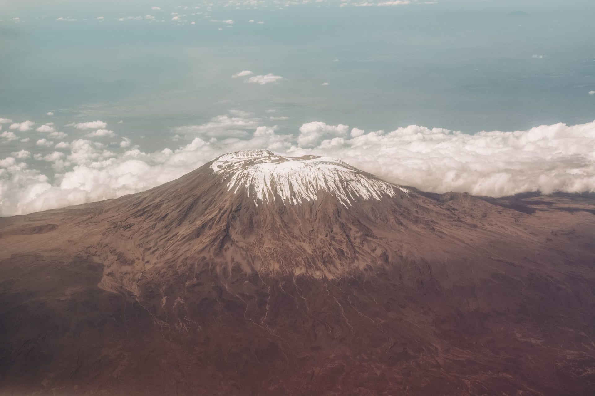 Kilimanjaro's snow-dusted peak rising above a layer of clouds over the Tanzanian plains at dawn