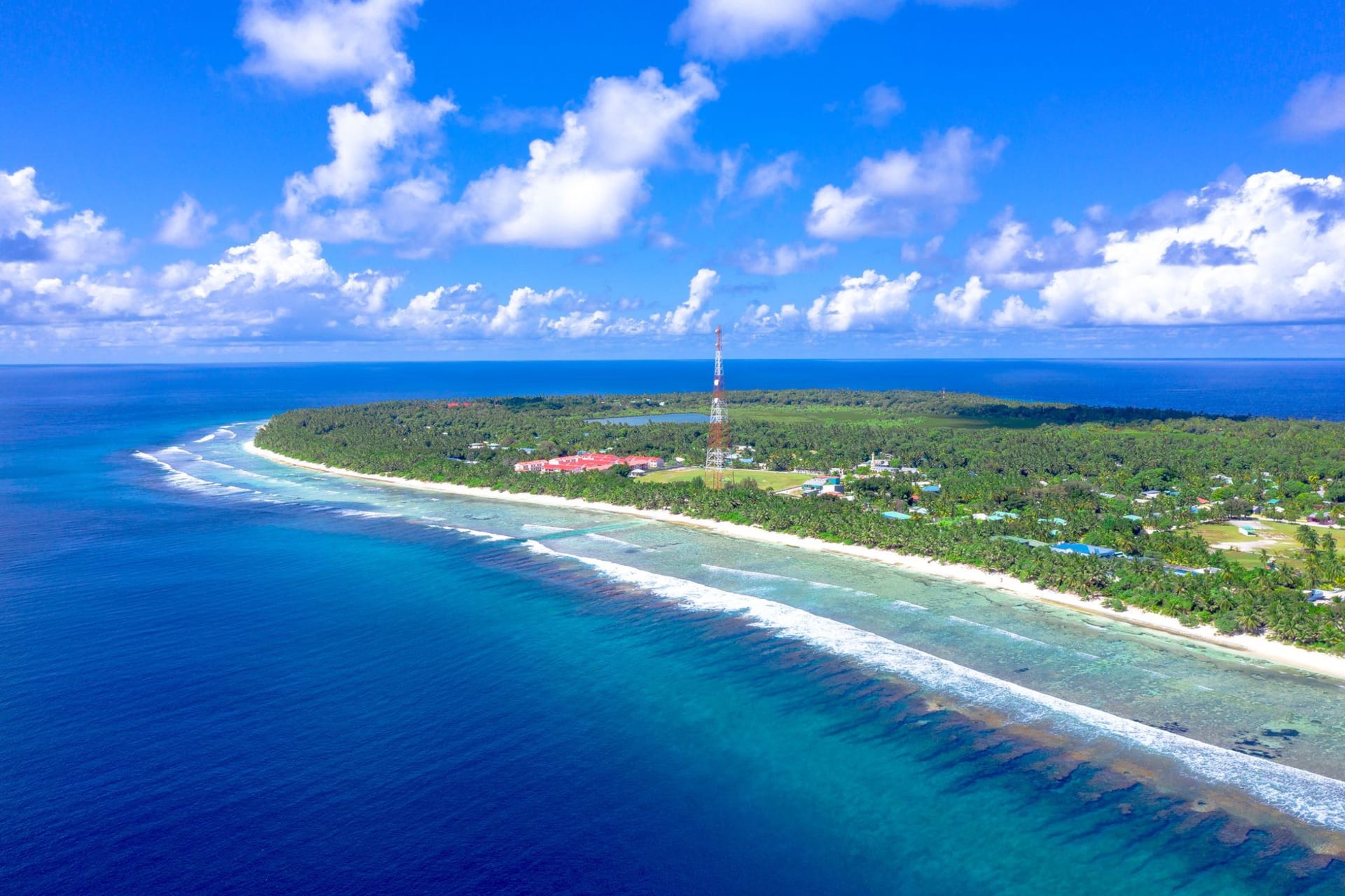 Long narrow reef strip of Tabiteuea viewed from a boat, the island stretching to the horizon with a channel cutting through the middle