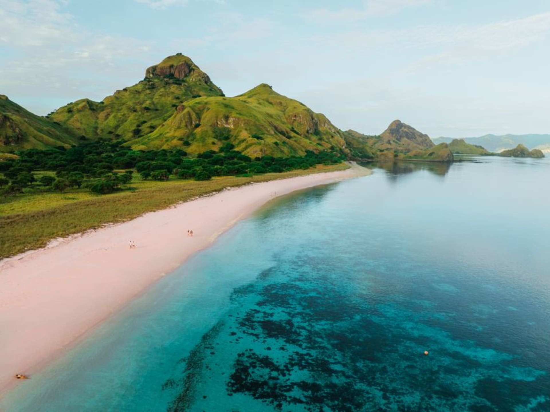 White sand beach on Kanawa Island fading into a shallow turquoise coral reef