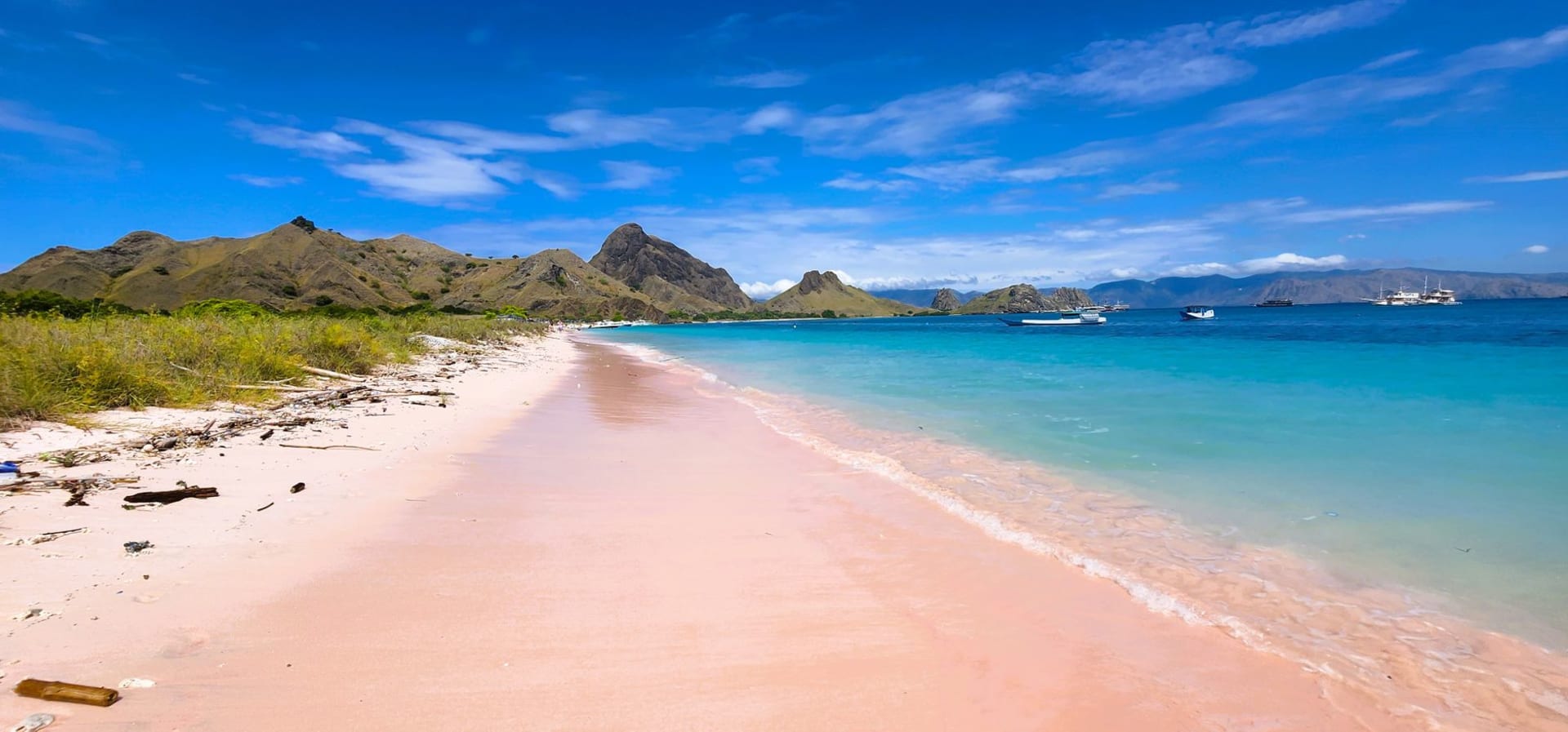 Pink sand beach and turquoise waters at Padar Island in Komodo National Park, Indonesia, with volcanic hills in the background
