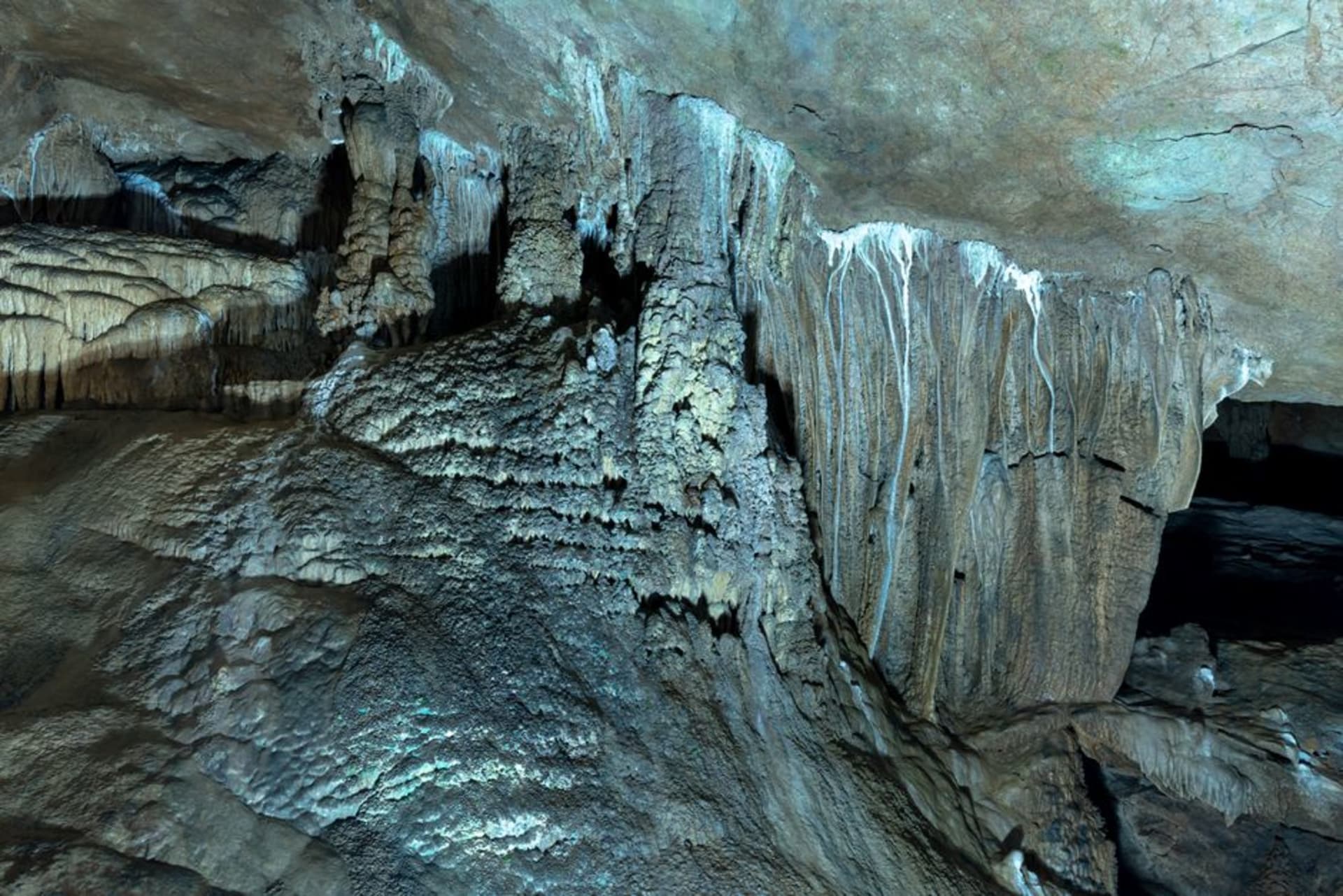 Illuminated walkway winding past stalactites and stalagmites inside the Marble Cave of Gadime